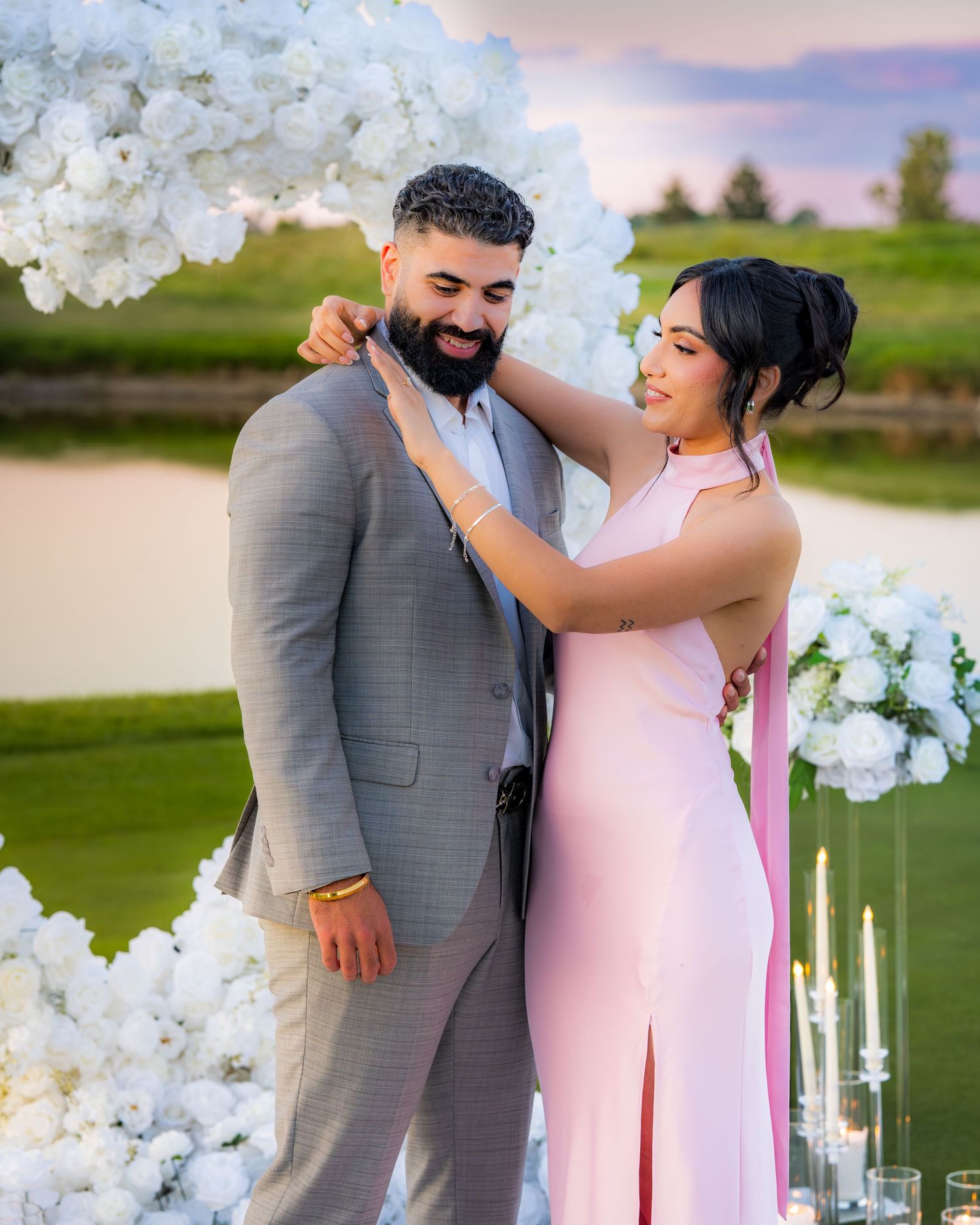 A couple laughs together during their photoshoot on a golf course with decorative white flowers.