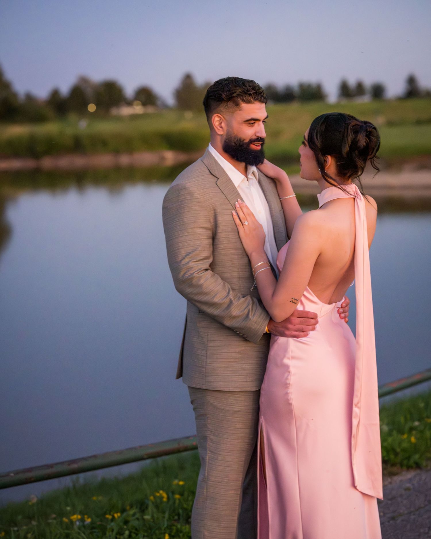 A sunset photoshoot captures a couple's tender moment by a serene lake.