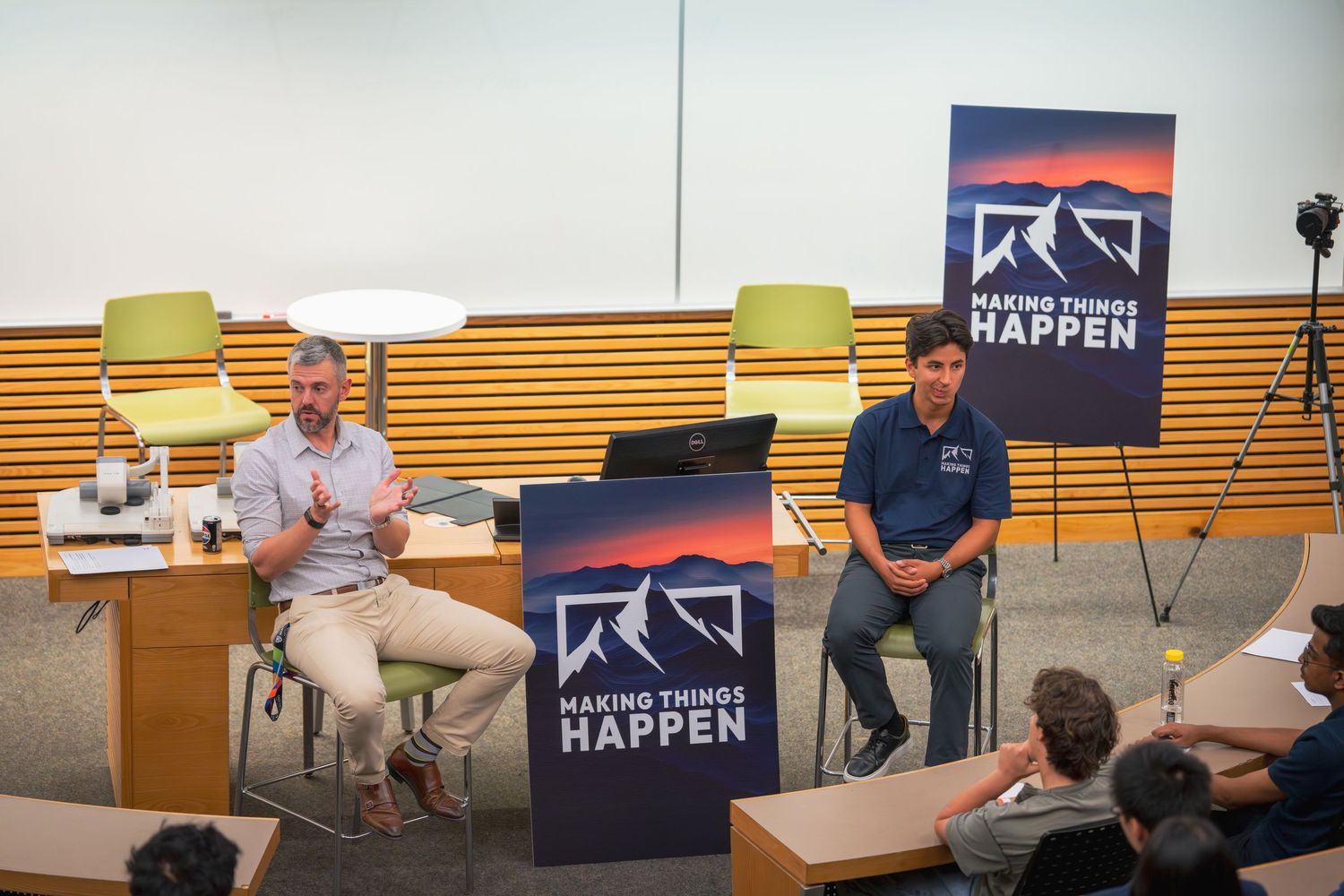 Wide view of presentation space with multiple screens and branded signage.