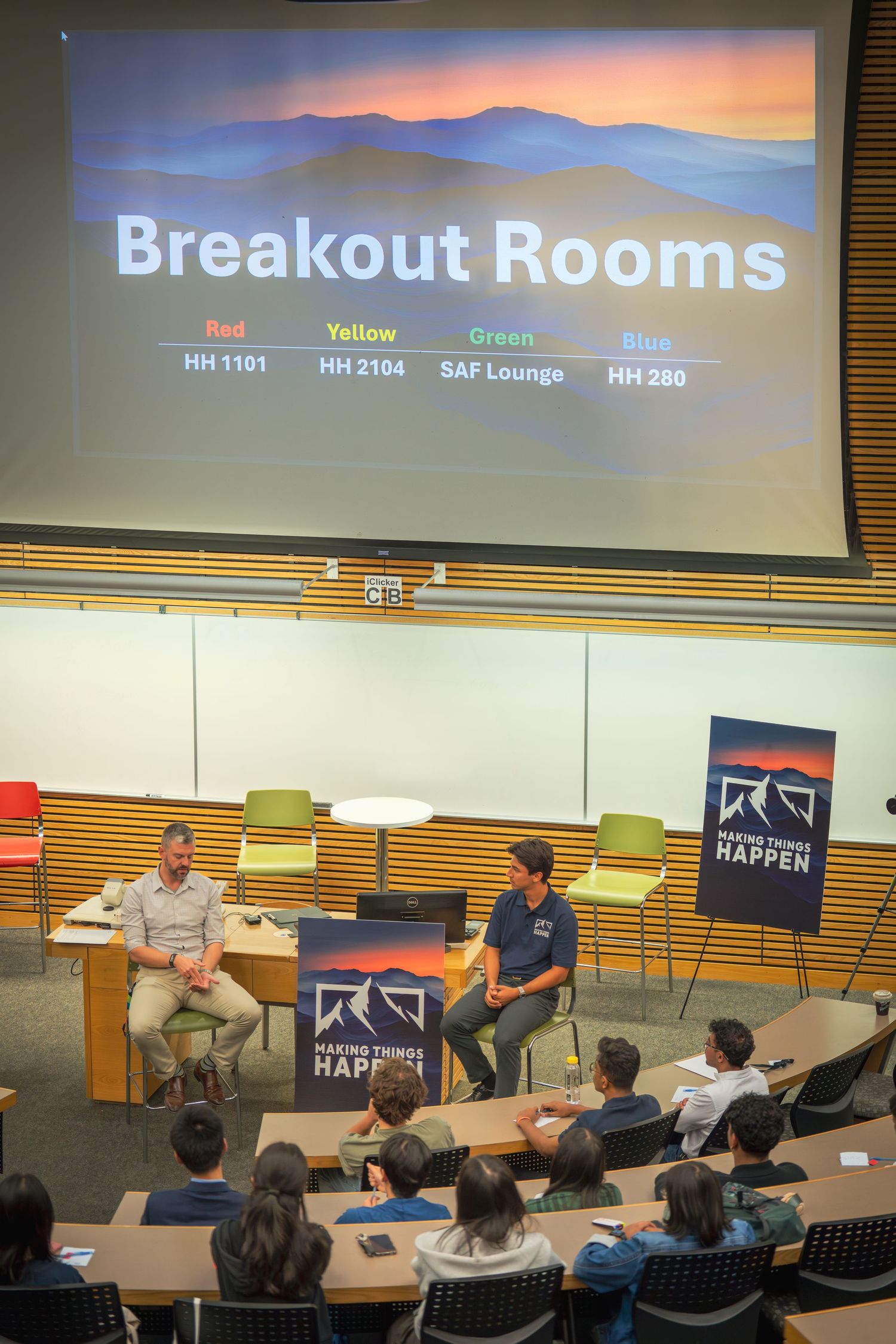 Conference room setup showing projector screen and audience seating with mountain themed branding.
