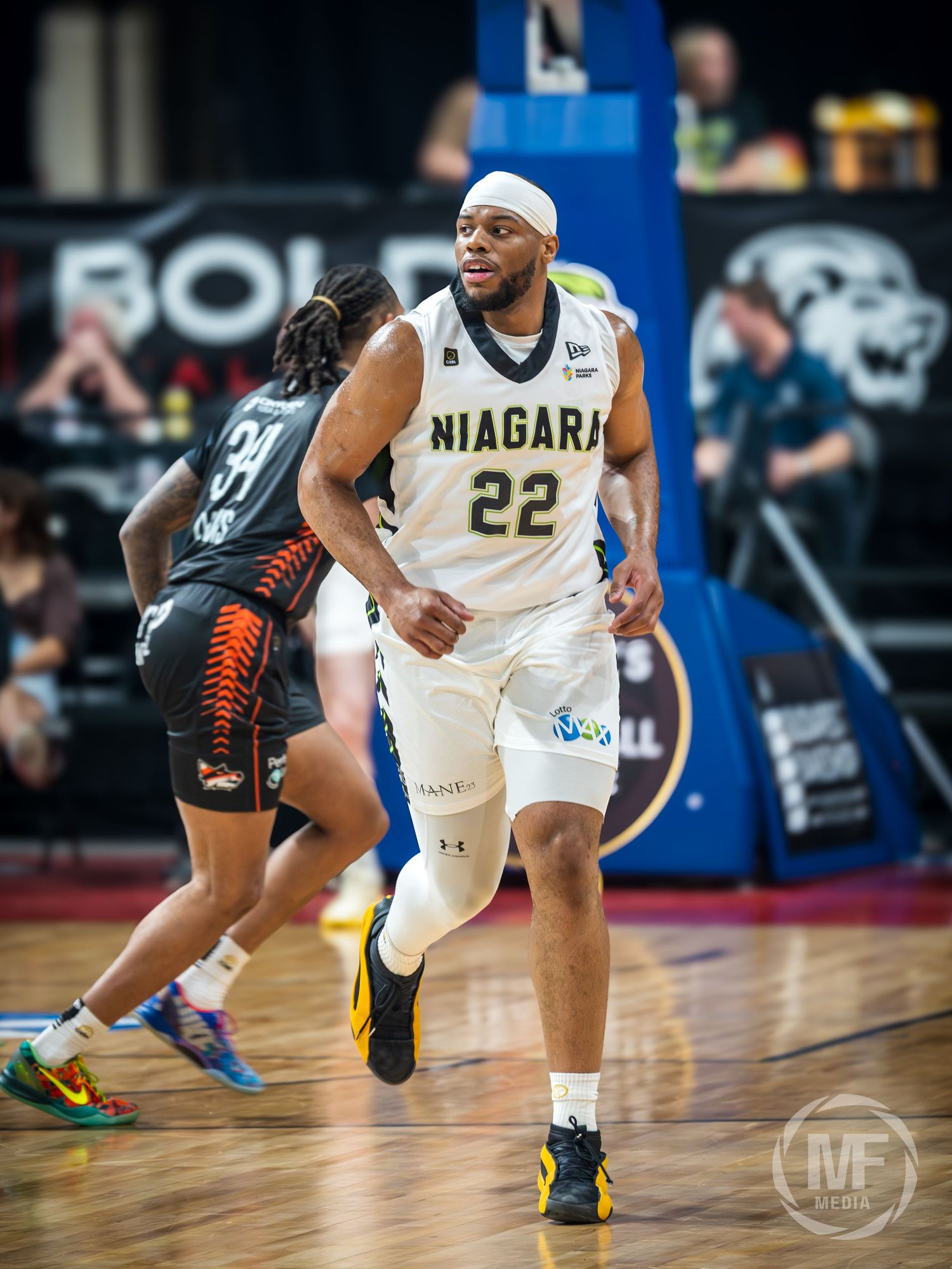 Niagara basketball player #22 in white uniform dribbles during a CEBL game against a opponent in black.