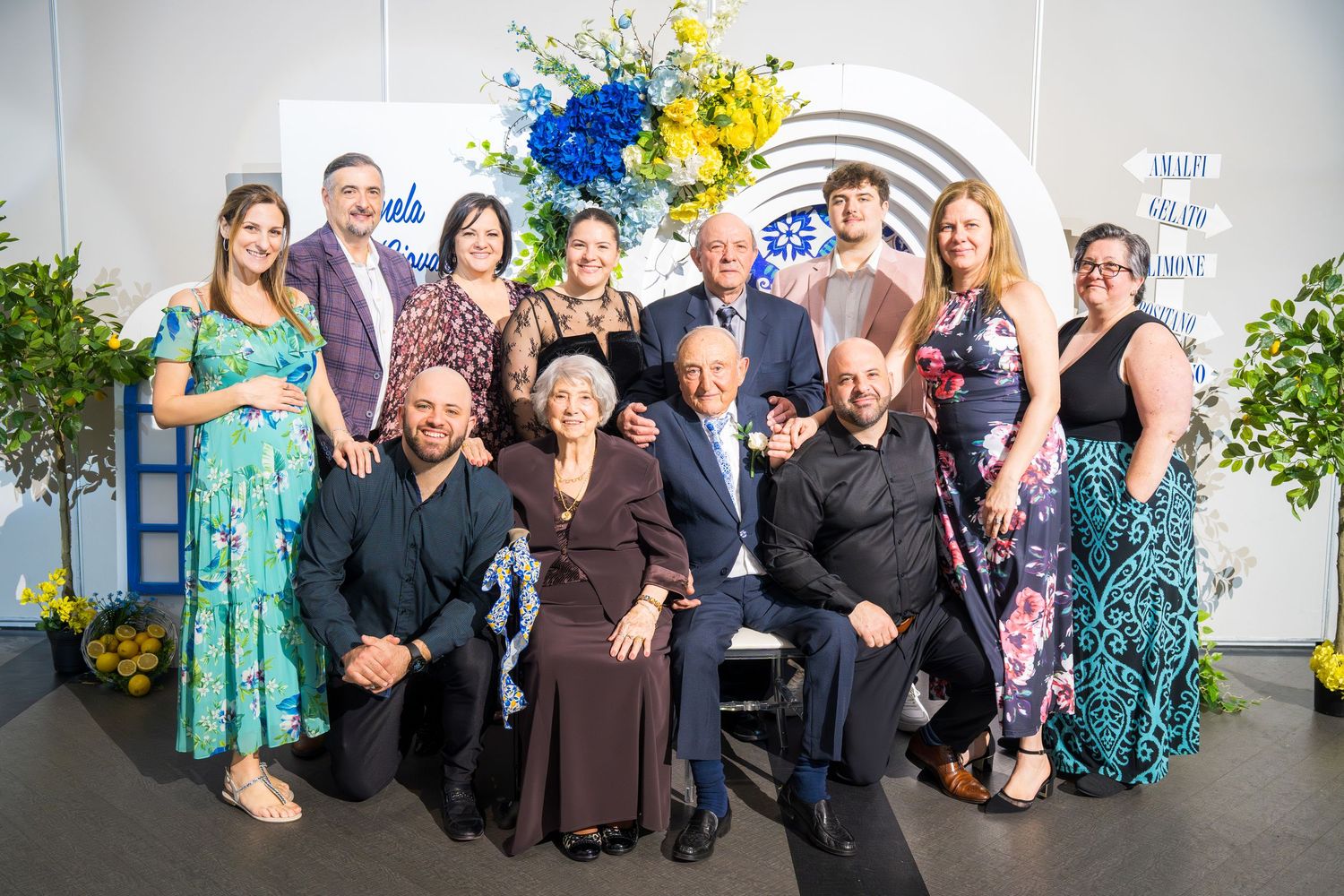 Large family group photo at anniversary celebration with blue and yellow floral decorations.