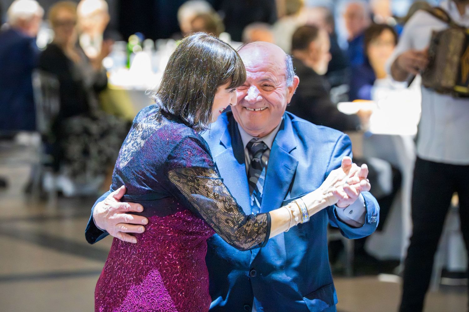 Elderly couple sharing a romantic dance embrace at a formal wedding reception celebration.