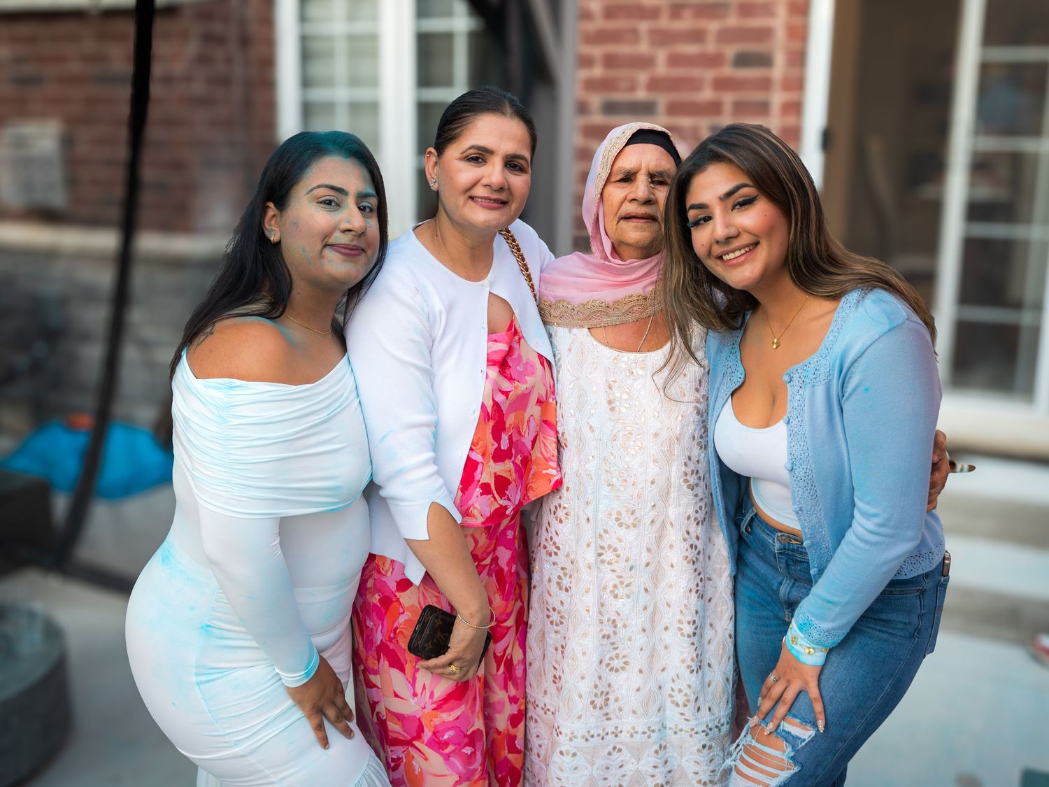 Four women of different generations smiling together outdoors at a family celebration party.