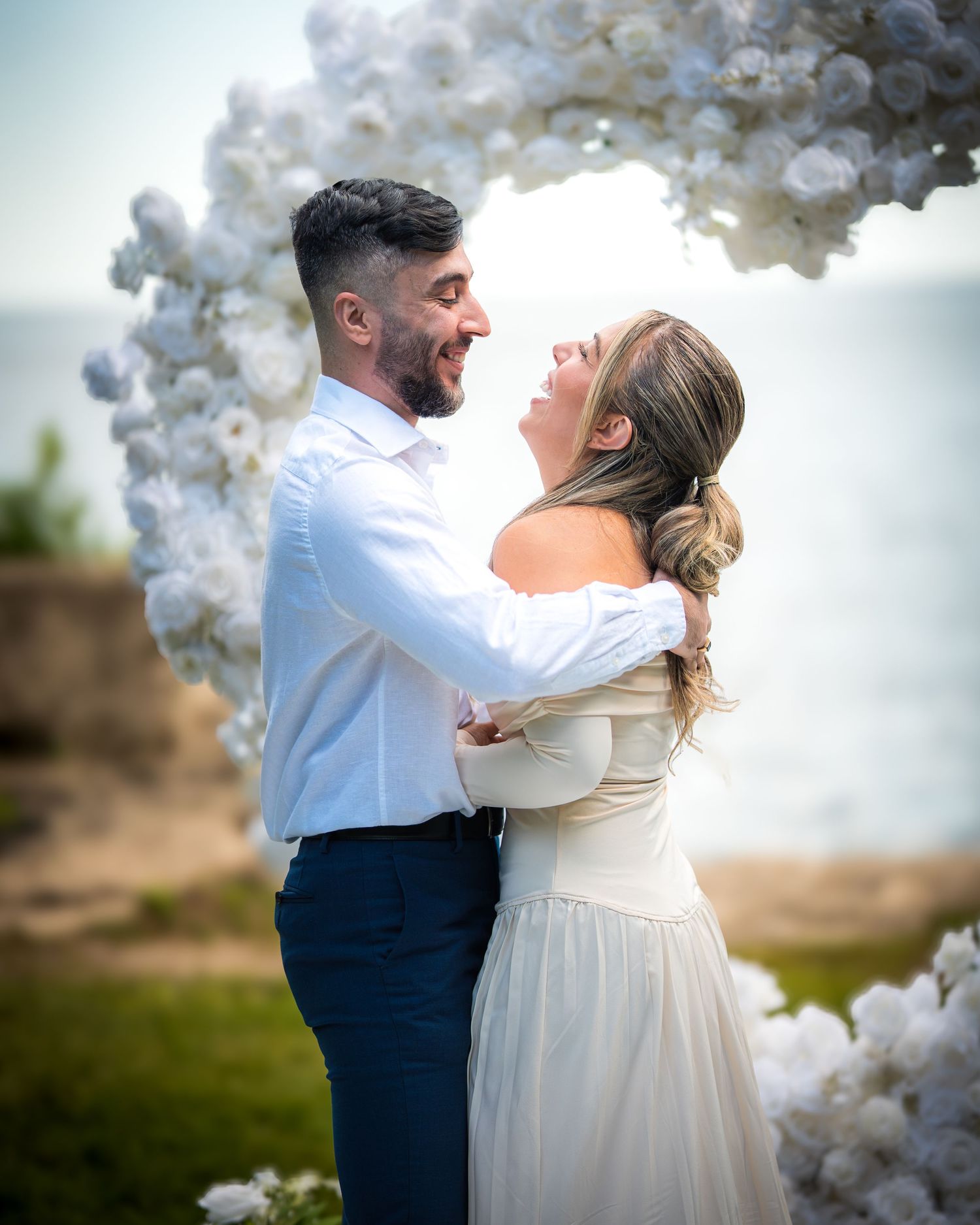 Romantic wedding dance under white balloon arch with coastal backdrop.
