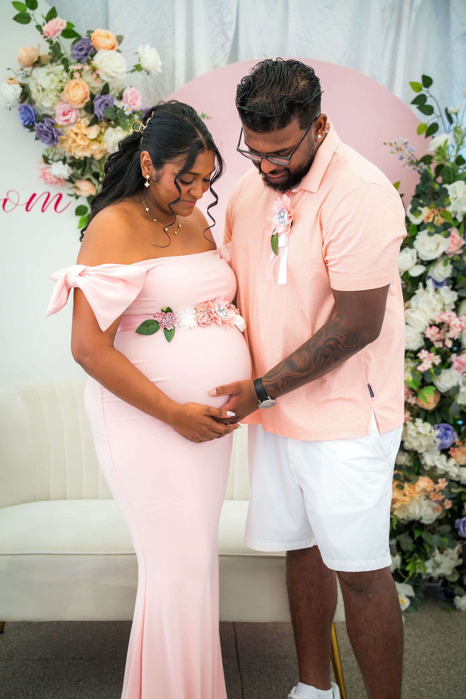 Intimate baby shower moment captured with pink and white floral decorations.