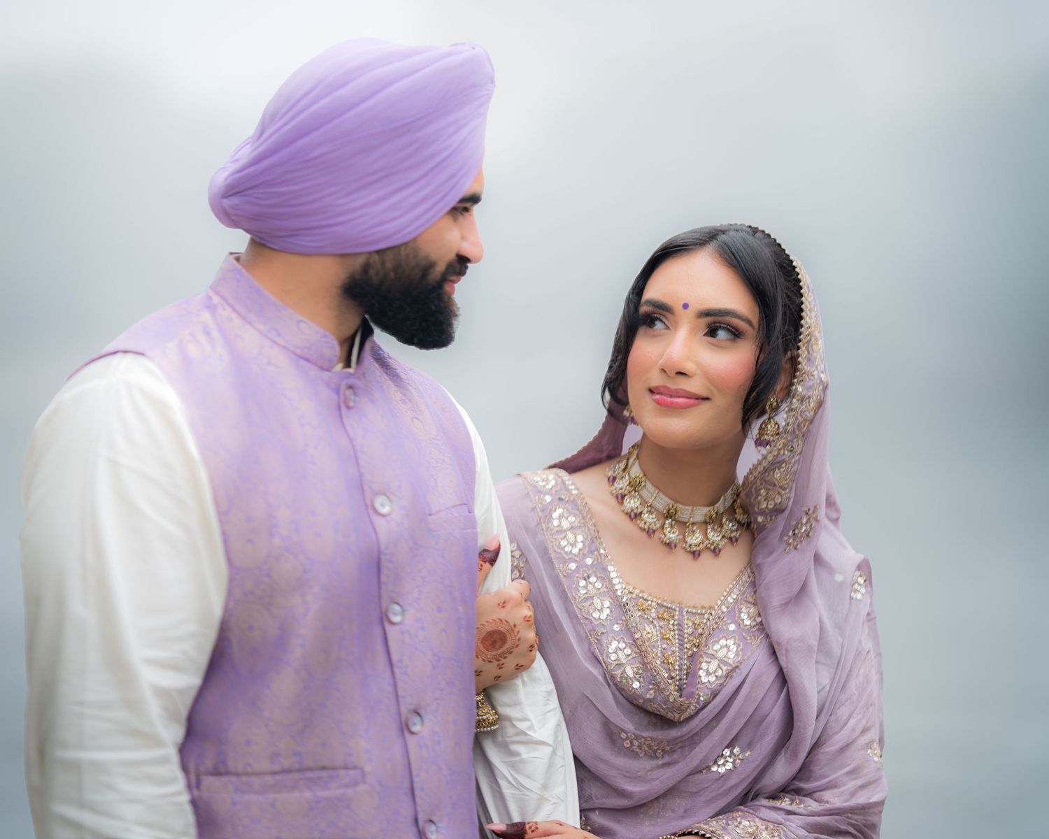 Couple in matching purple and white attire share tender moments during their photoshoot.