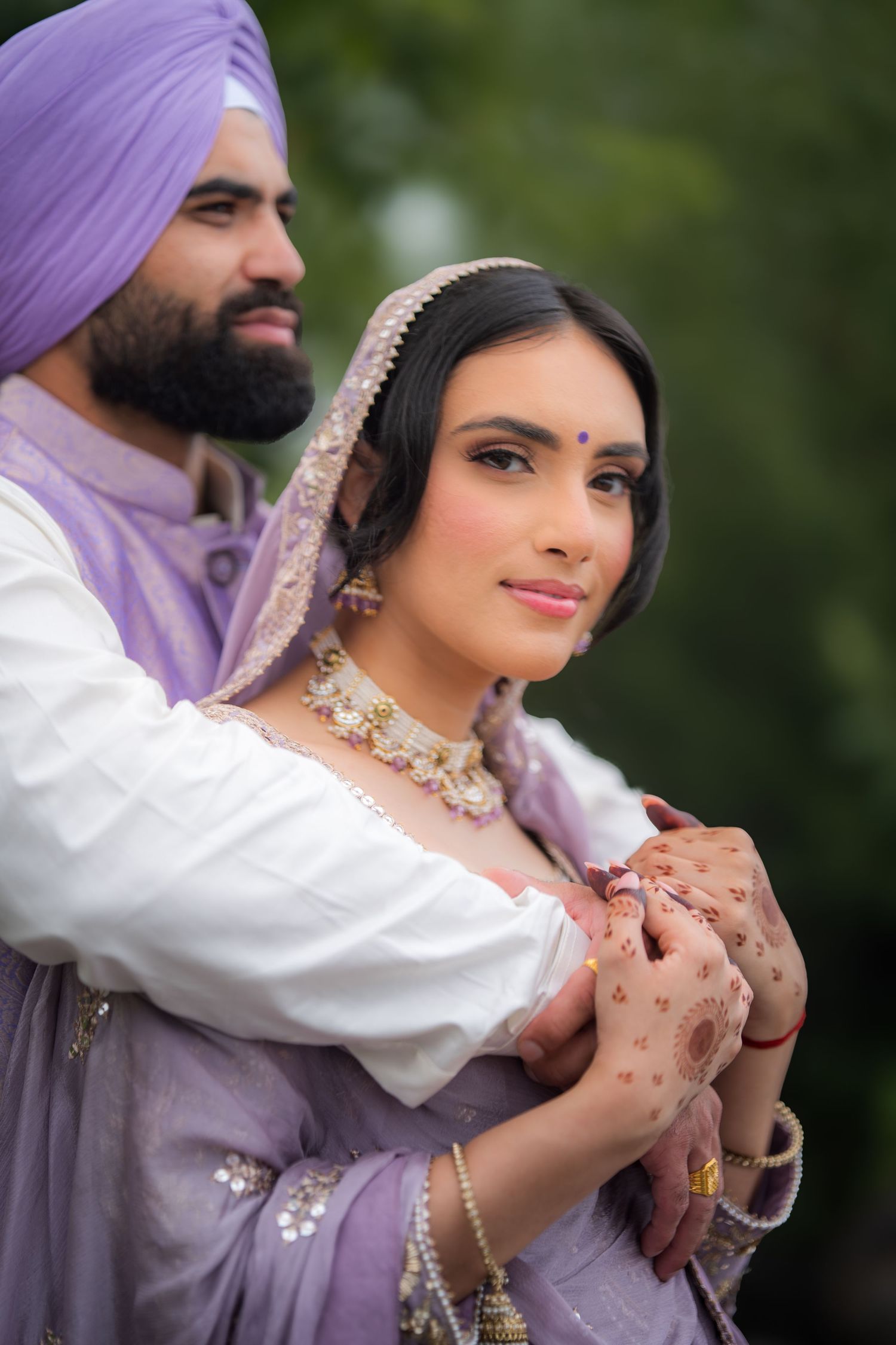 Intimate moment captured between couple in coordinated purple and white traditional Indian outfits.