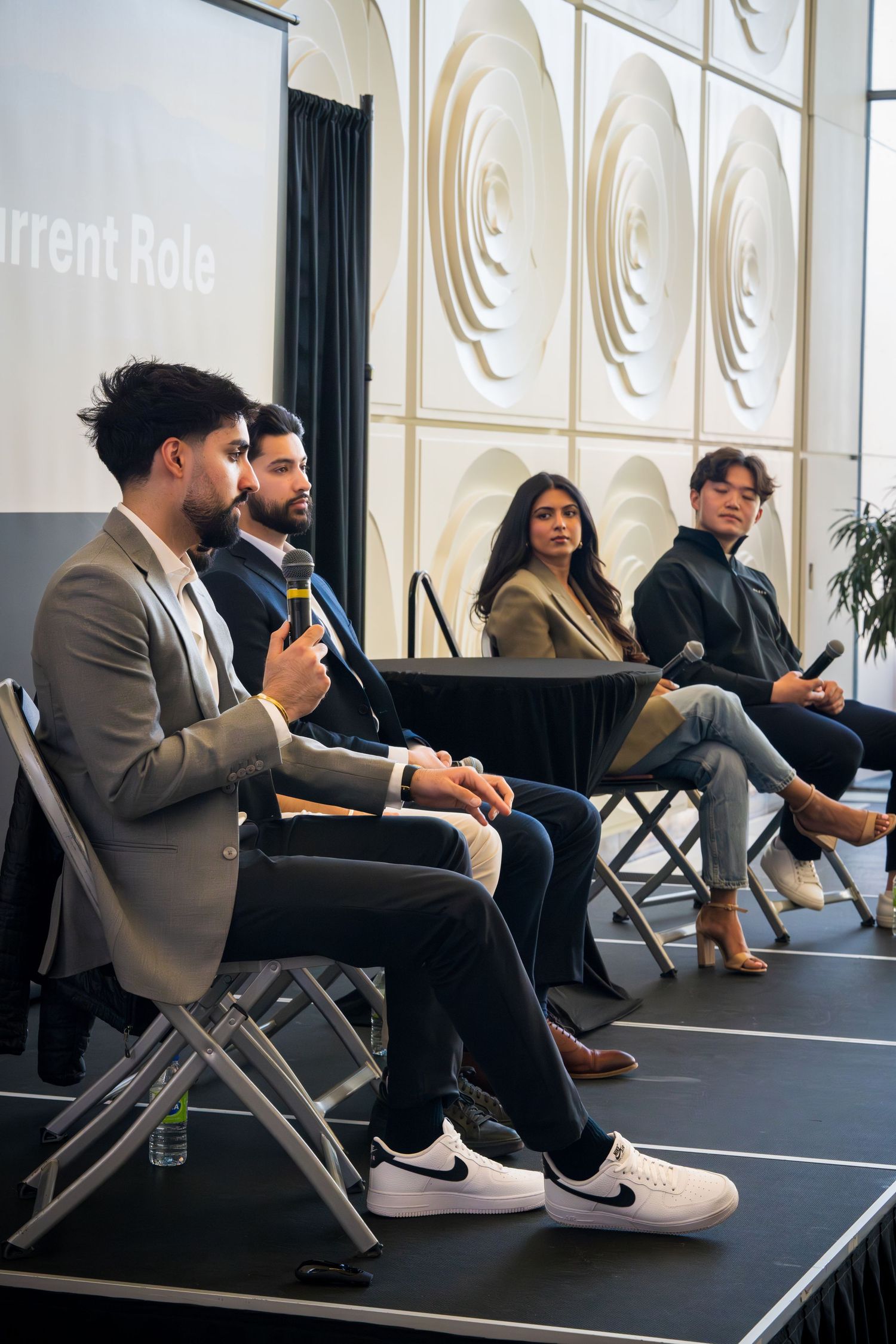 Business panel discussion with speakers seated on stage with modern wall design.