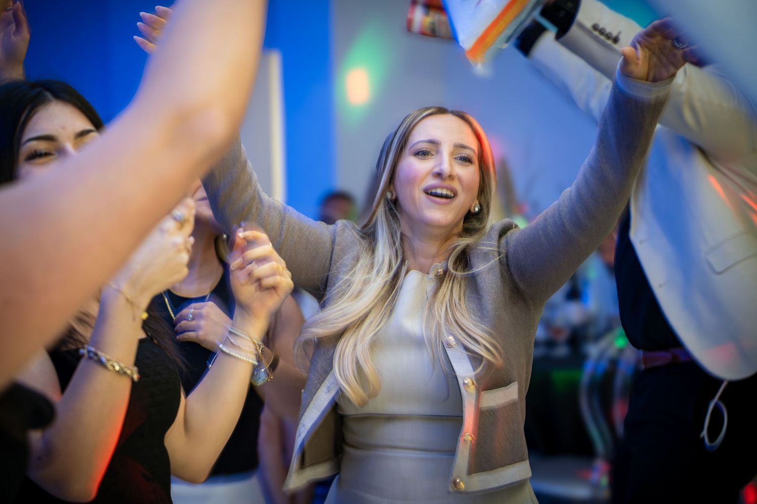 Energetic party scene with people dancing under blue lighting and disco effects.