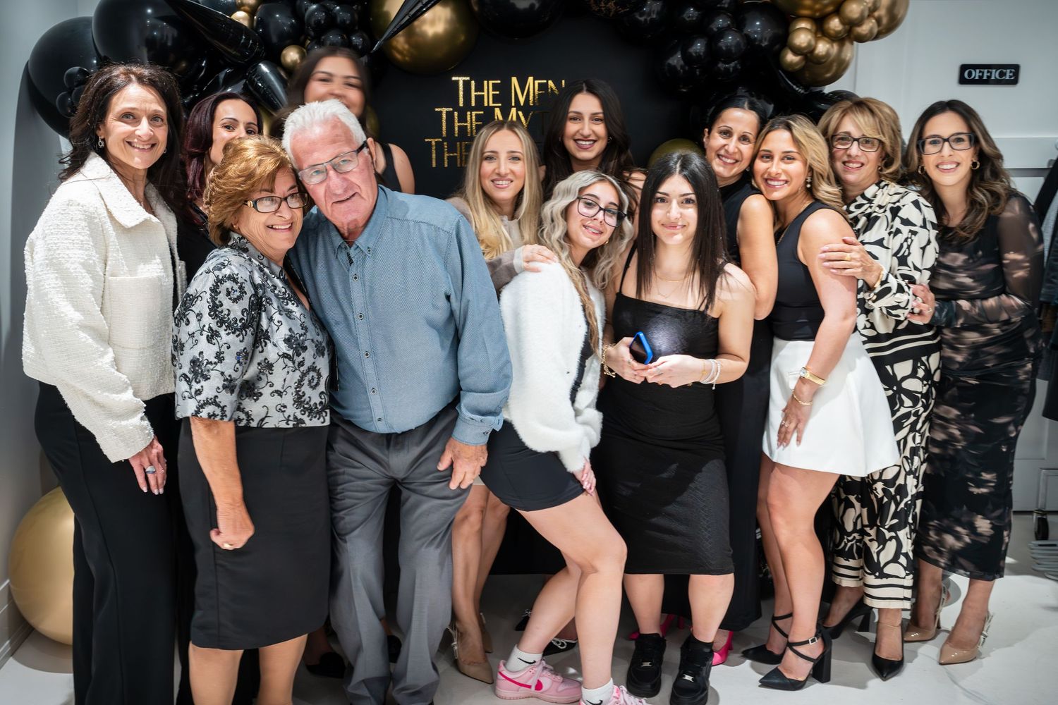 Party guests lined up for group photo with elegant balloon arrangements.