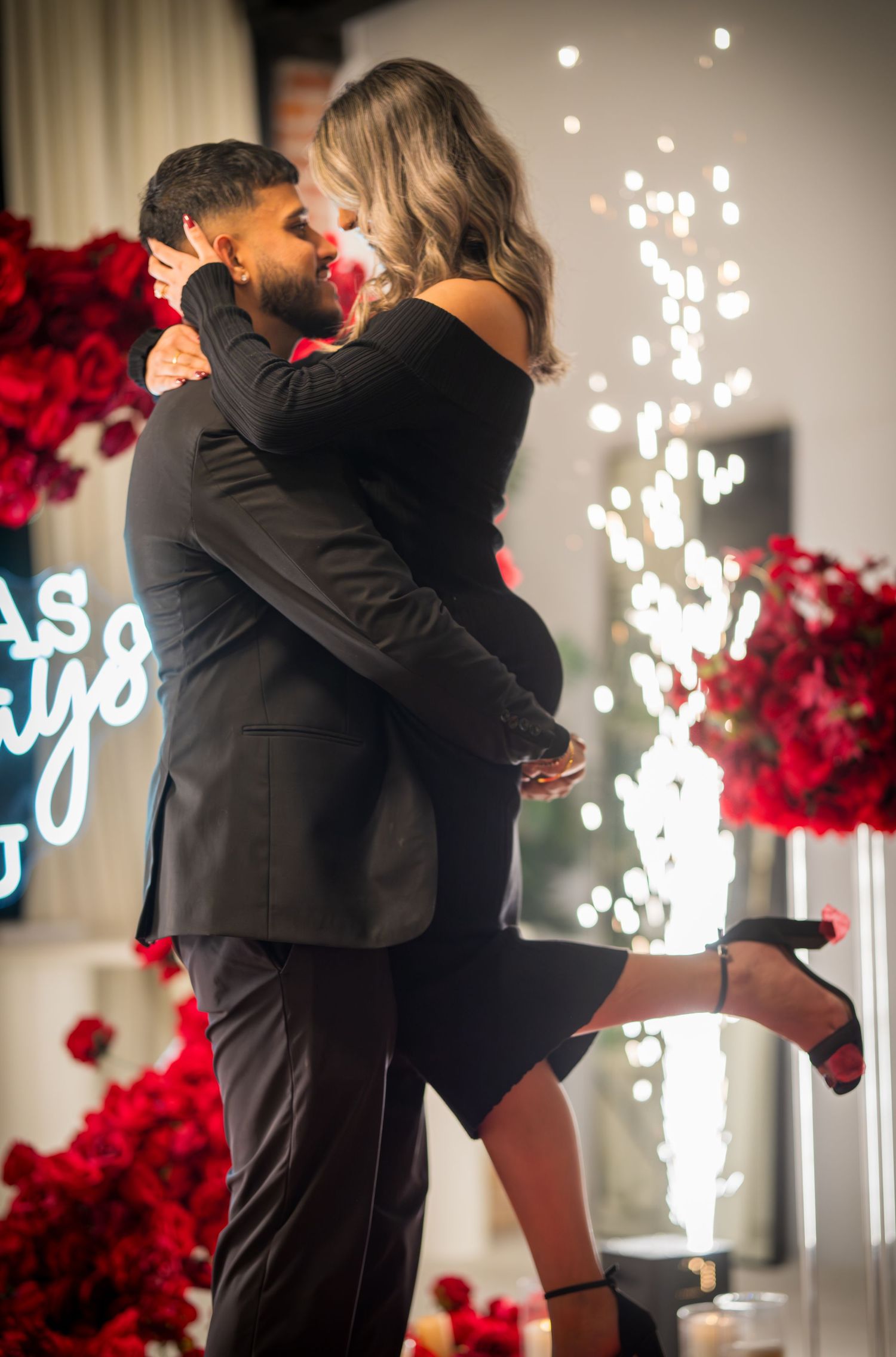 A romantic proposal scene with red rose decor and neon lighting in the background.