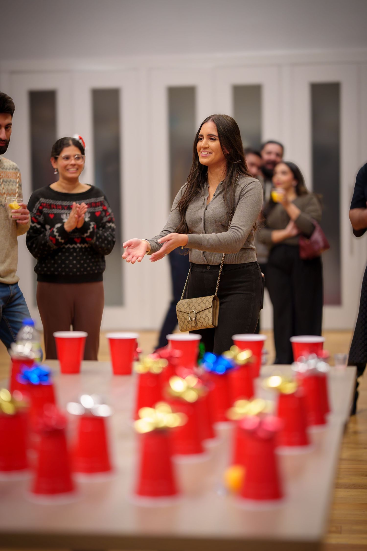 Red party cups arranged in rows on wooden table during social gathering.