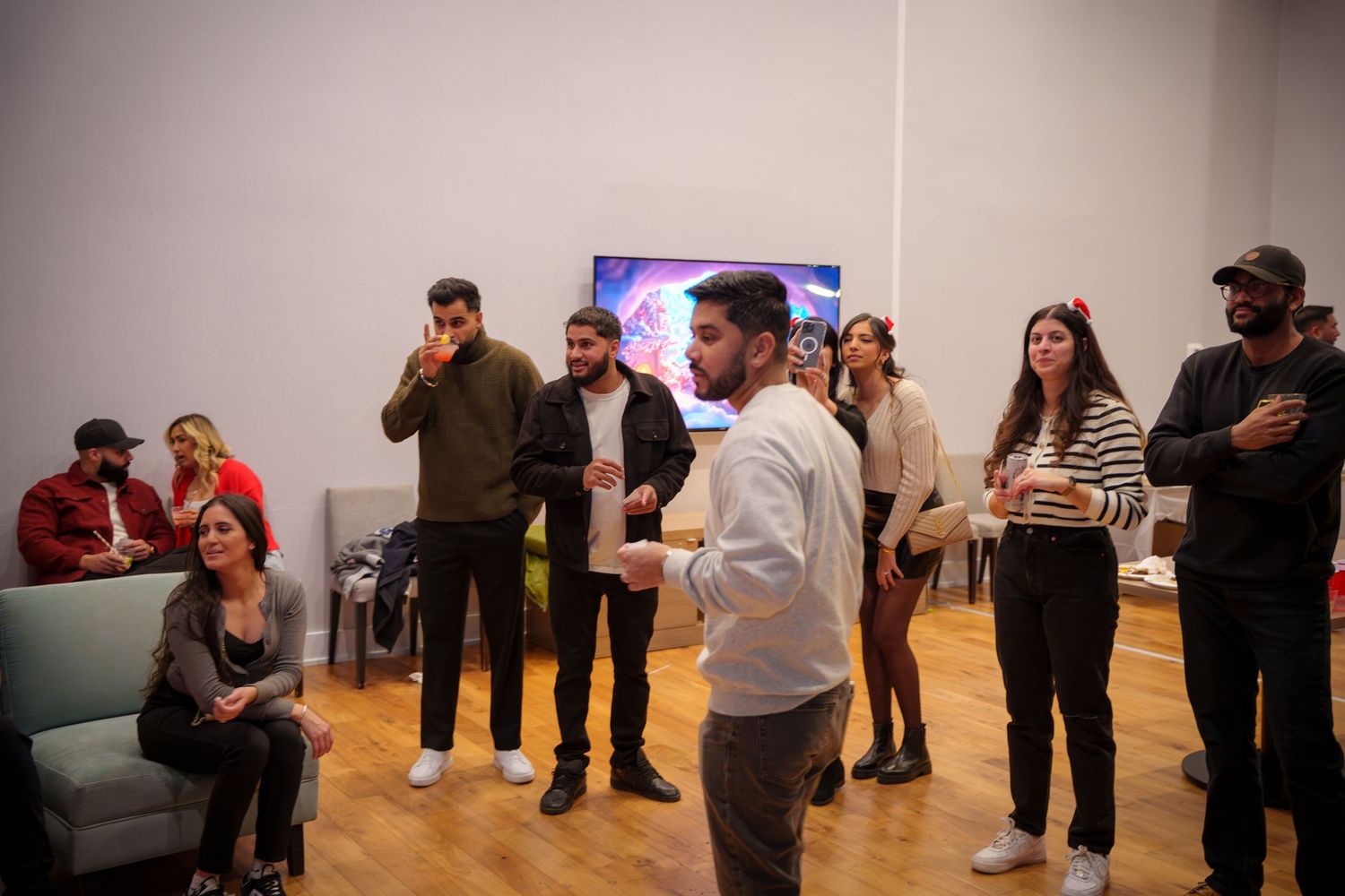Casual gathering of people standing and socializing in a modern room with hardwood floors.