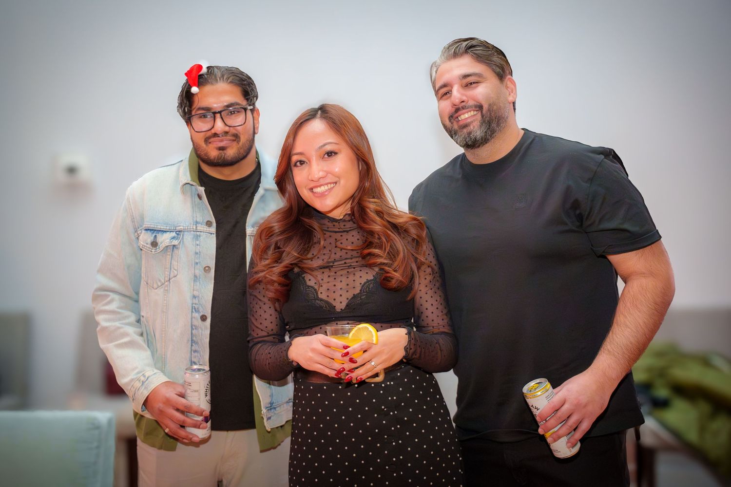 Three friends pose together at an indoor social gathering.