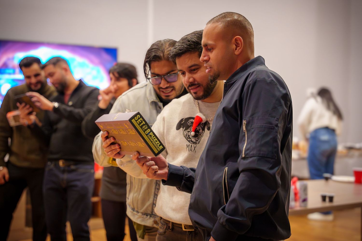 People gathered in a circle looking down at items they are holding during an indoor event.