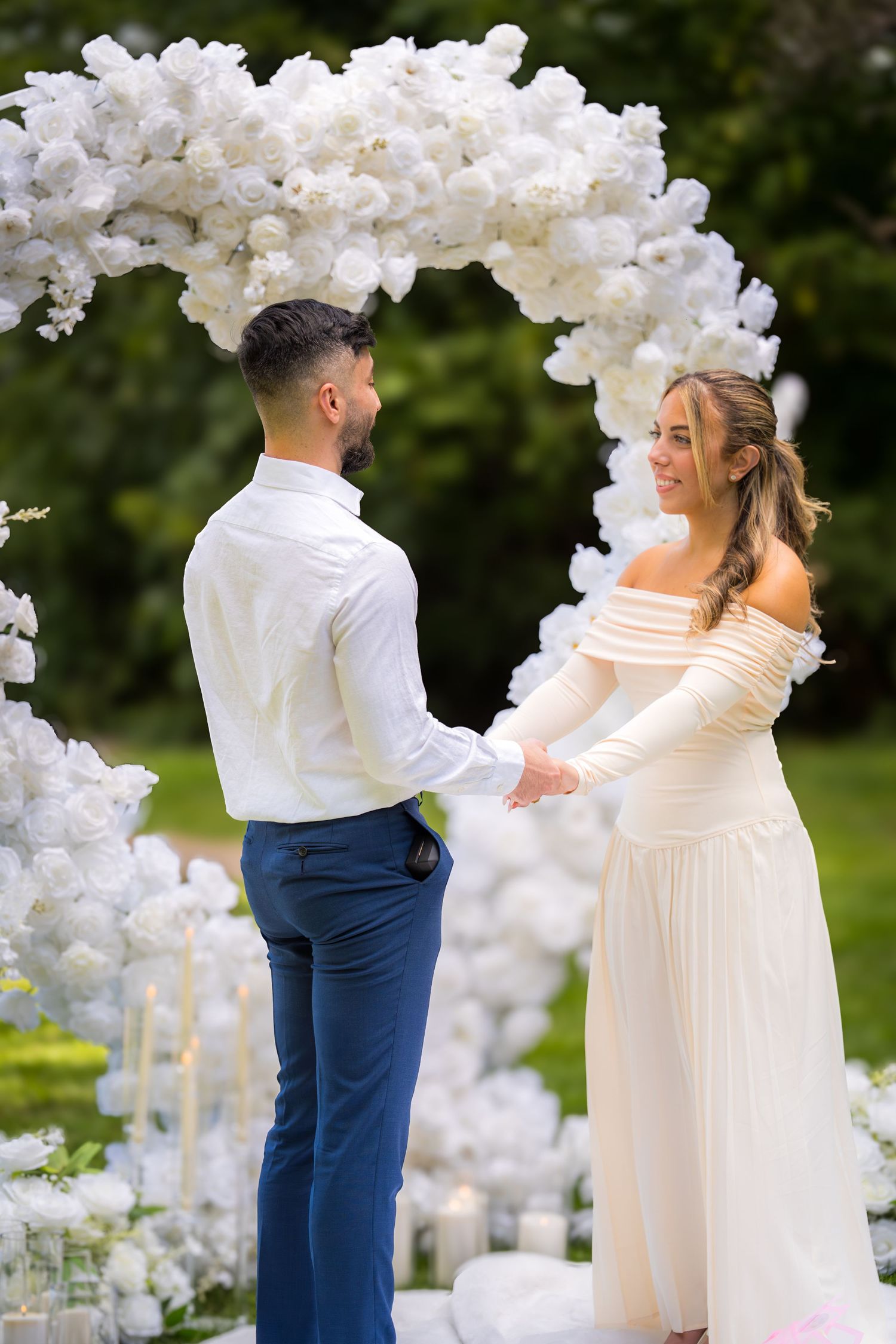 A couple sharing their first dance under an elegant white floral arch at their garden wedding.