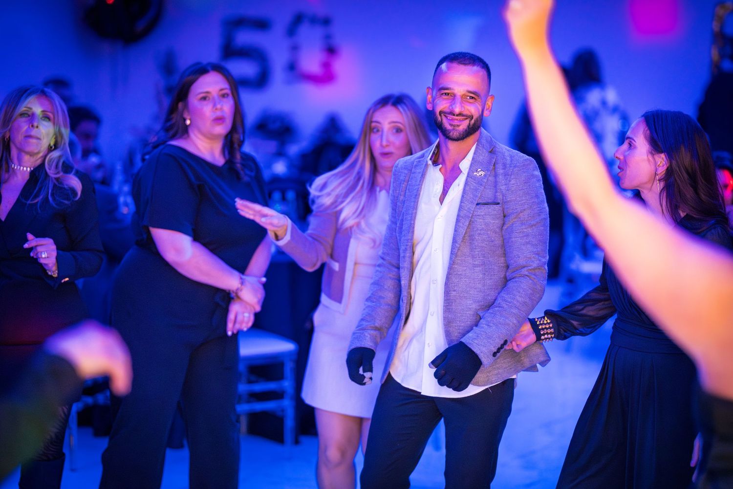 Partygoers dancing and enjoying themselves under vibrant blue lighting.