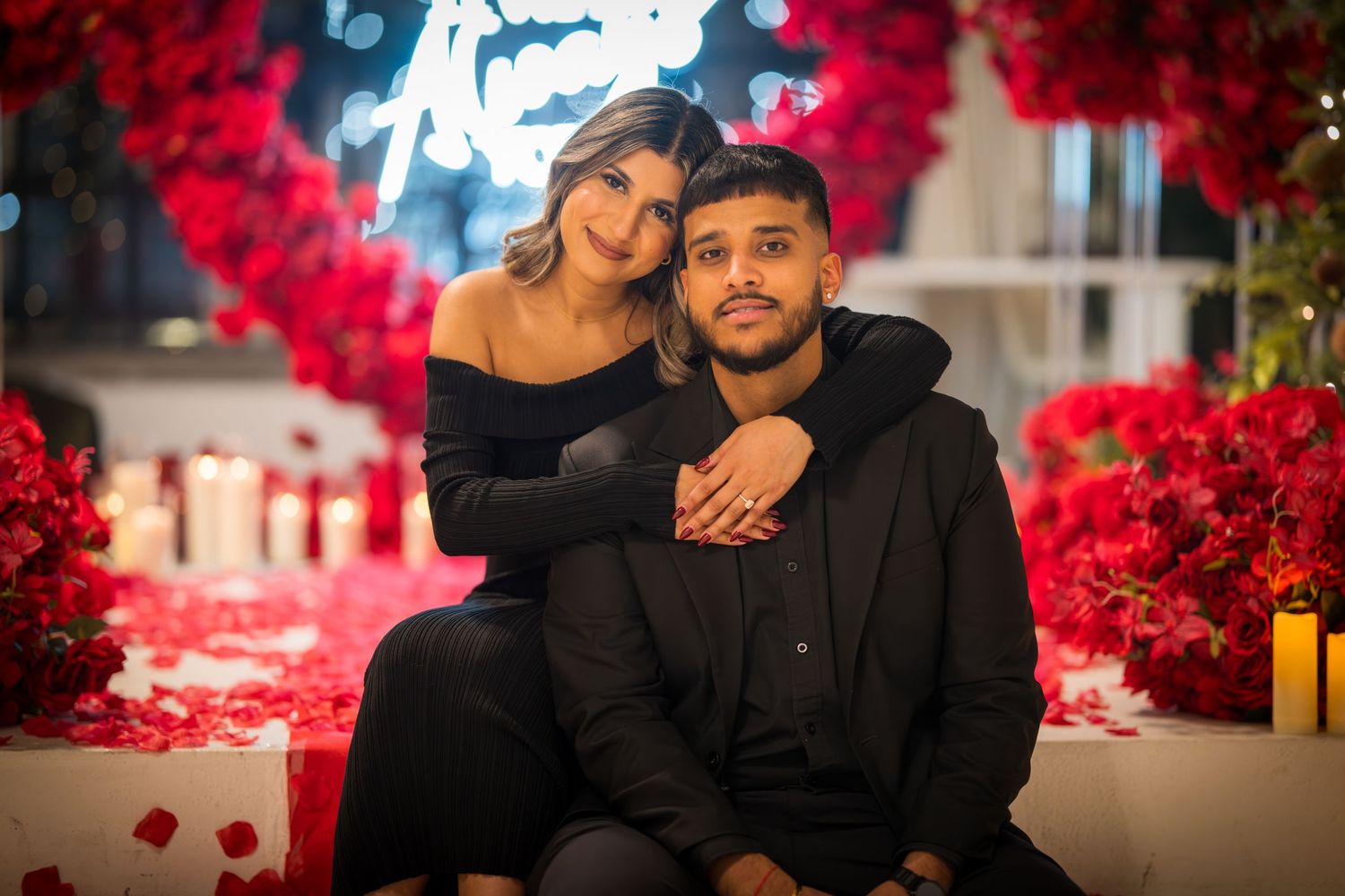 Intimate couple's photoshoot featuring black attire and dramatic red flower decorations.