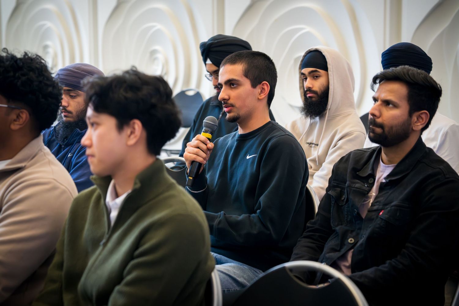 Conference attendees in business attire engage in discussion while seated in a modern venue.