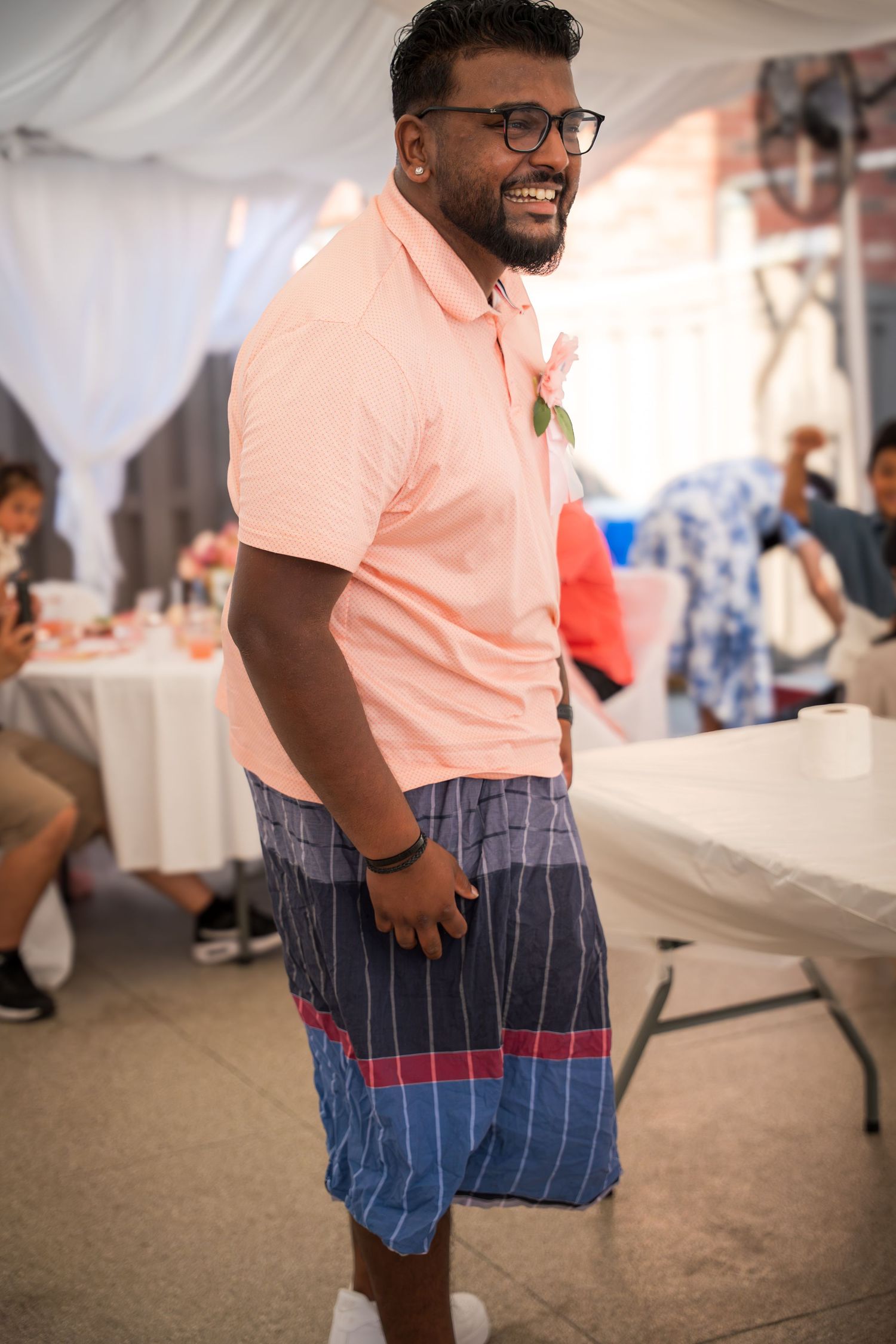 Person in a peach polo and striped shorts smiling at an indoor event.