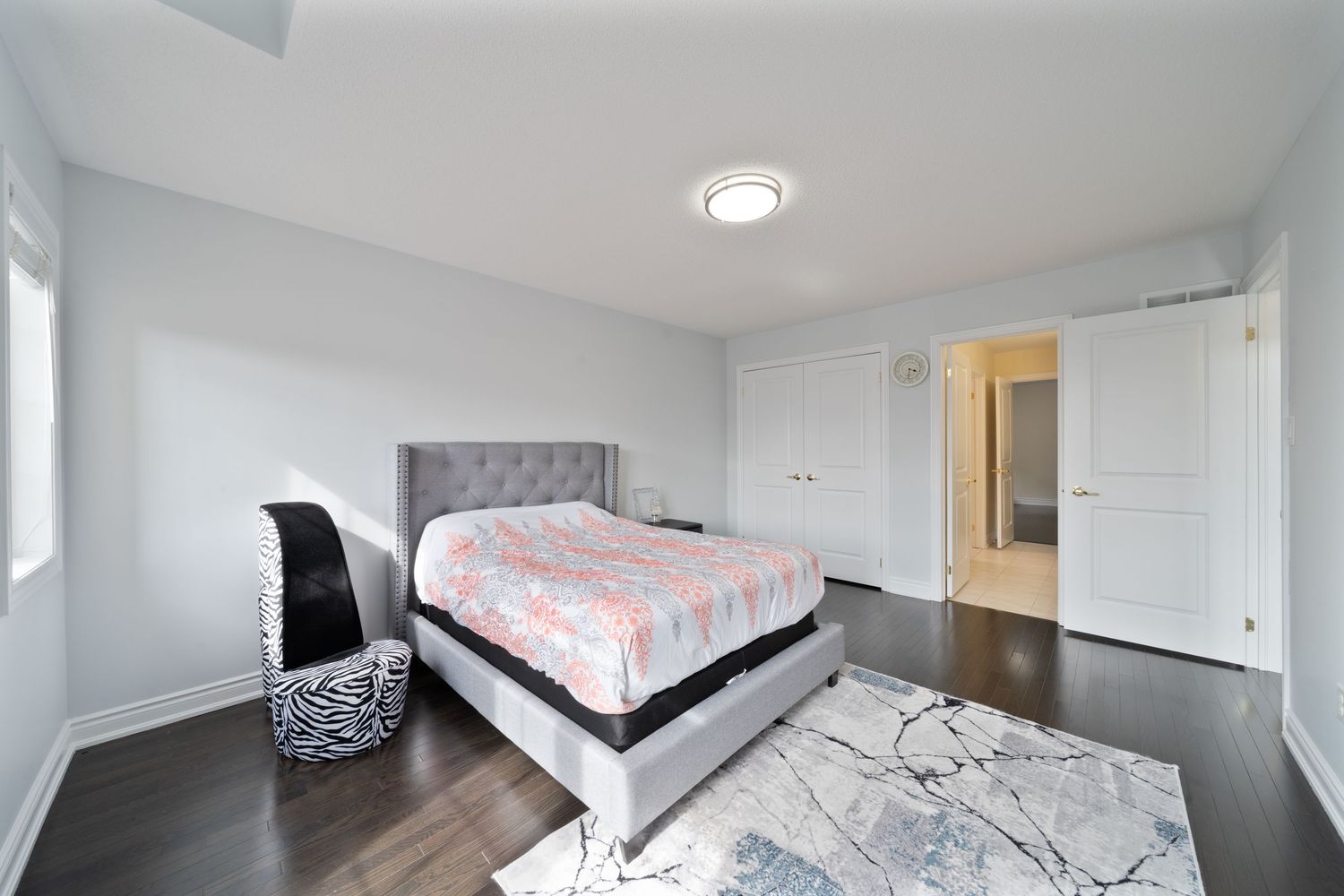 Modern bedroom interior with white walls, dark hardwood floors, and recessed lighting showcasing a minimalist design style.