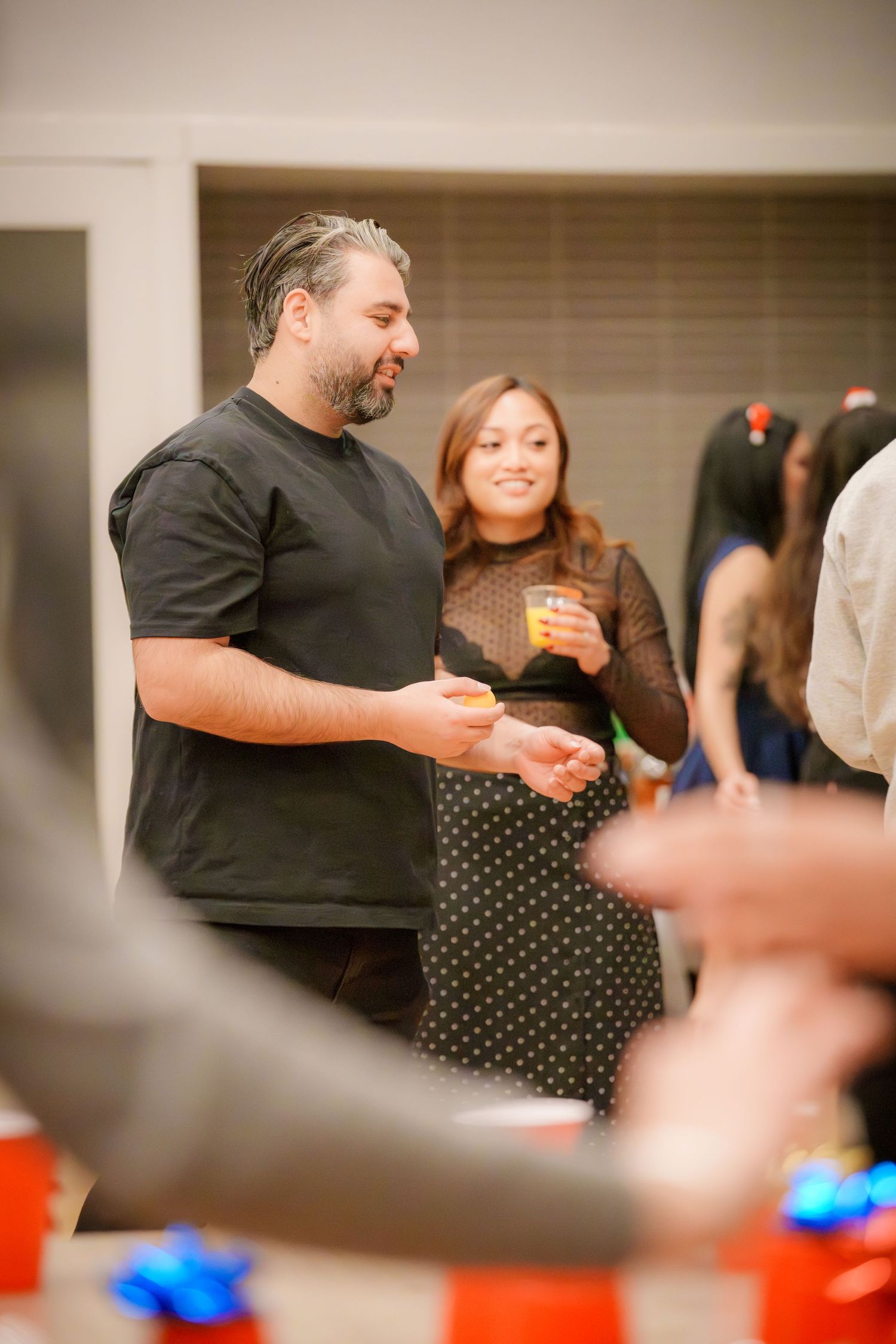 Guests mingling and socializing at an indoor celebration with festive lighting.