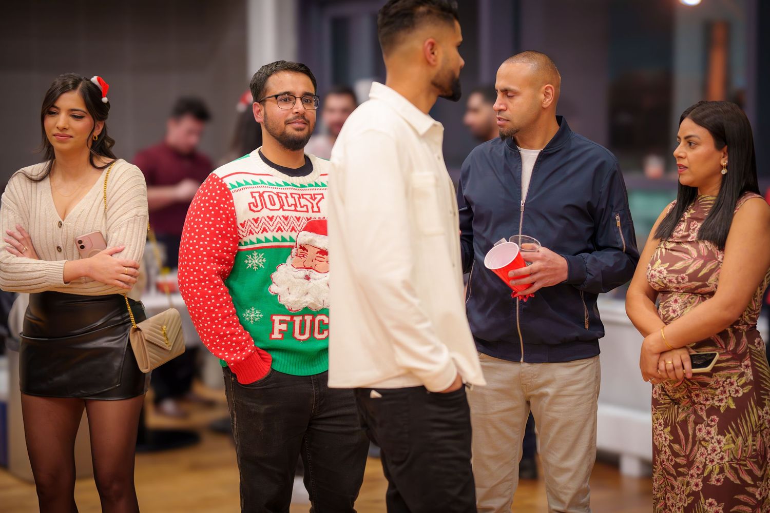 People gathered at a holiday party wearing festive sweaters and casual attire.