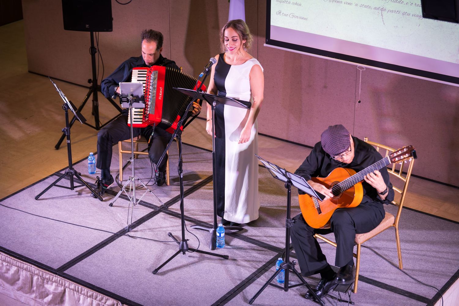 Female vocalist performs on stage with accordion and guitar players during Neapolitan Ice Cream musical showcase.