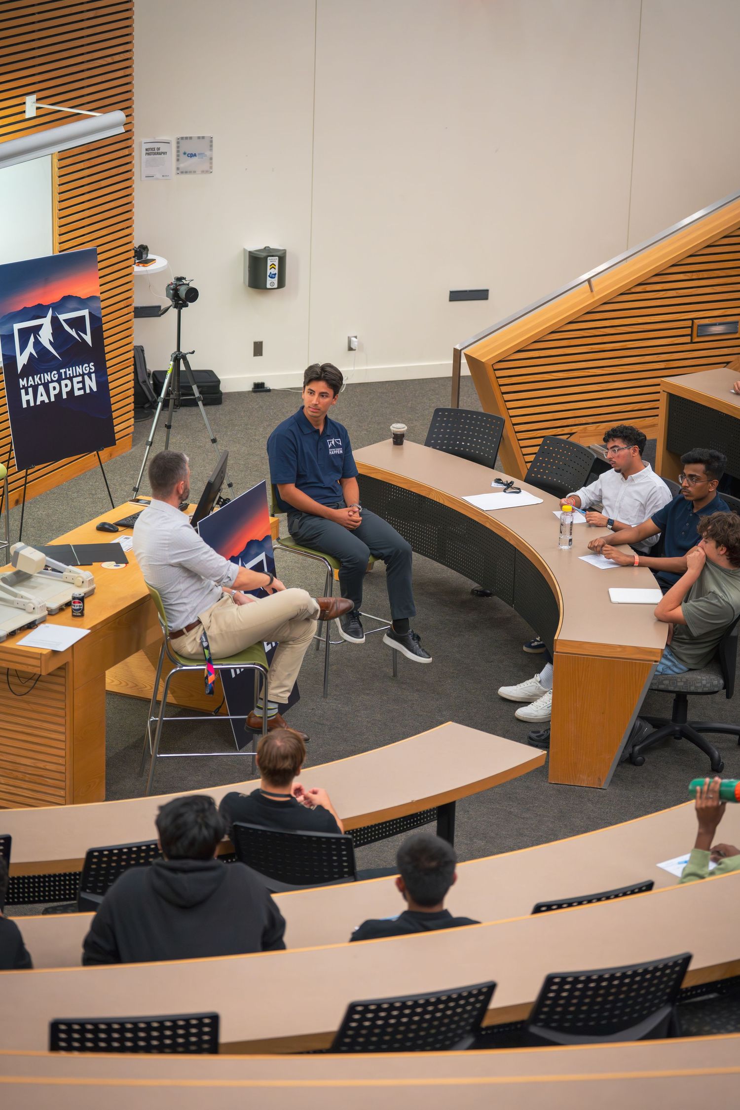 Attendees participate in a discussion within a tiered lecture hall with modern furnishings.
