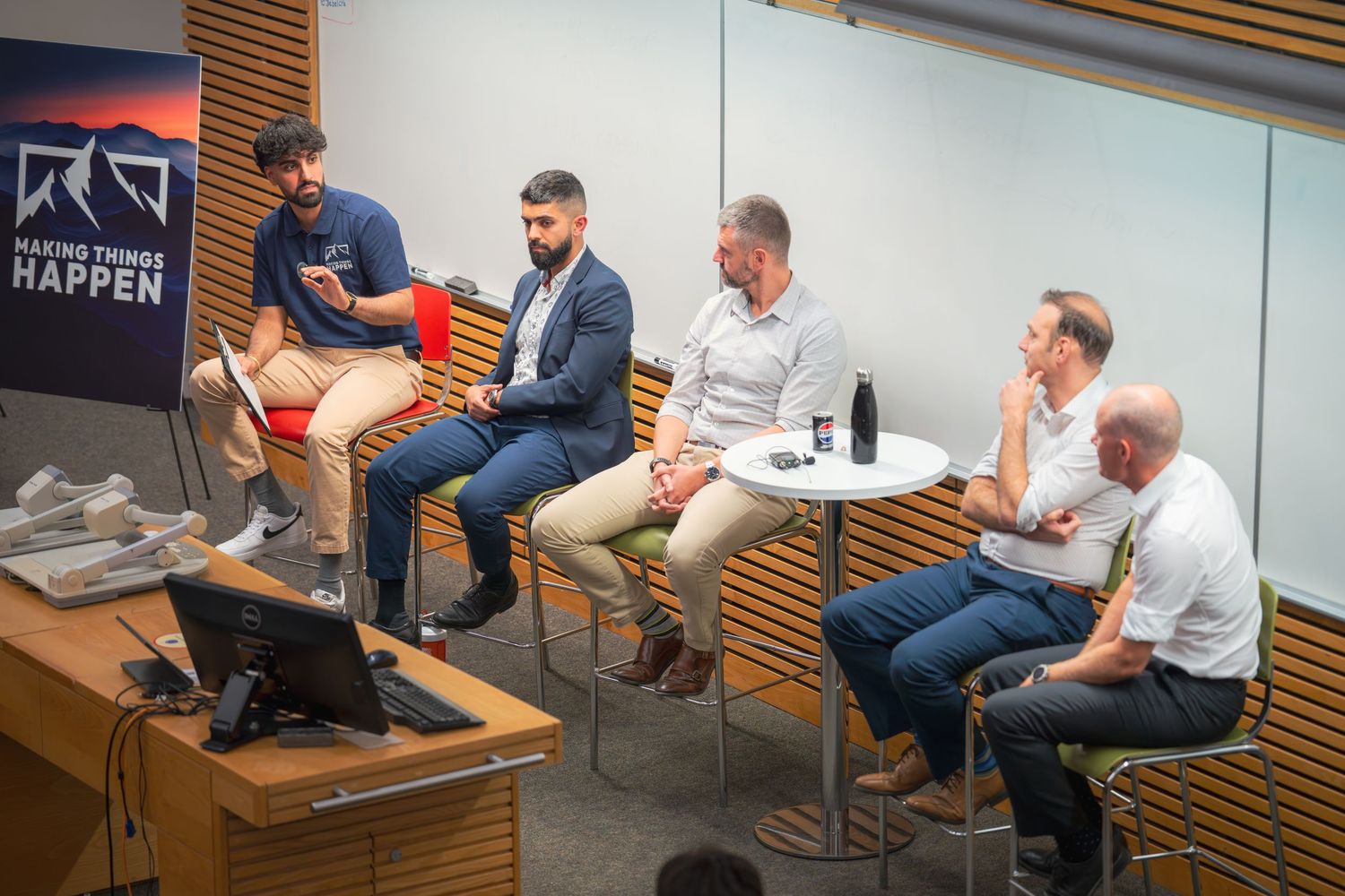 Conference room meeting with multiple attendees seated around curved table.