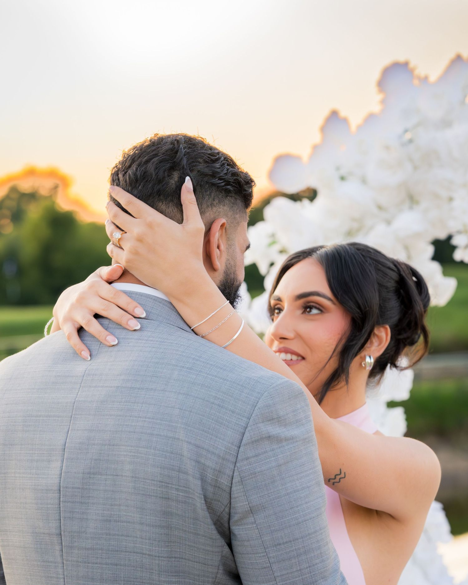 Romantic embrace captured during sunset with white balloon decorations.