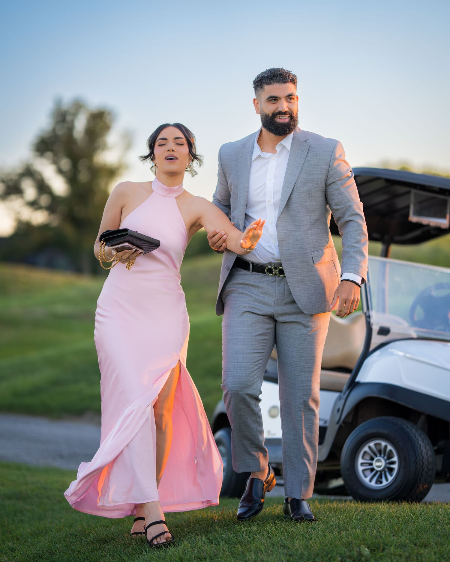 A couple walks together near a golf cart on a scenic course path.