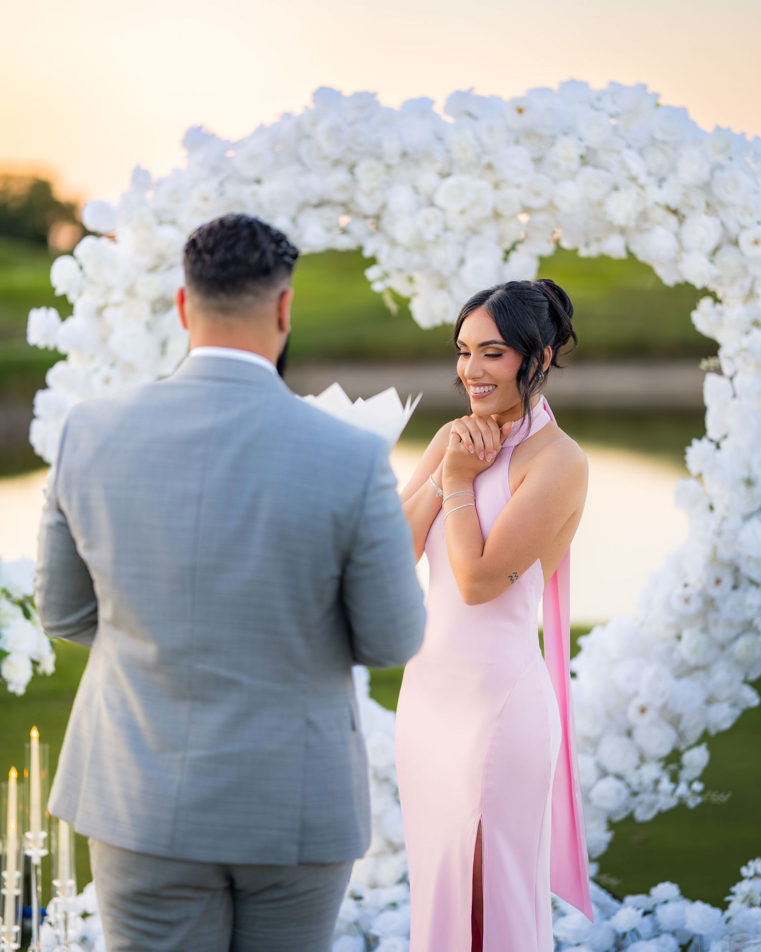 Surprise proposal captured under a luxurious white floral arch installation.