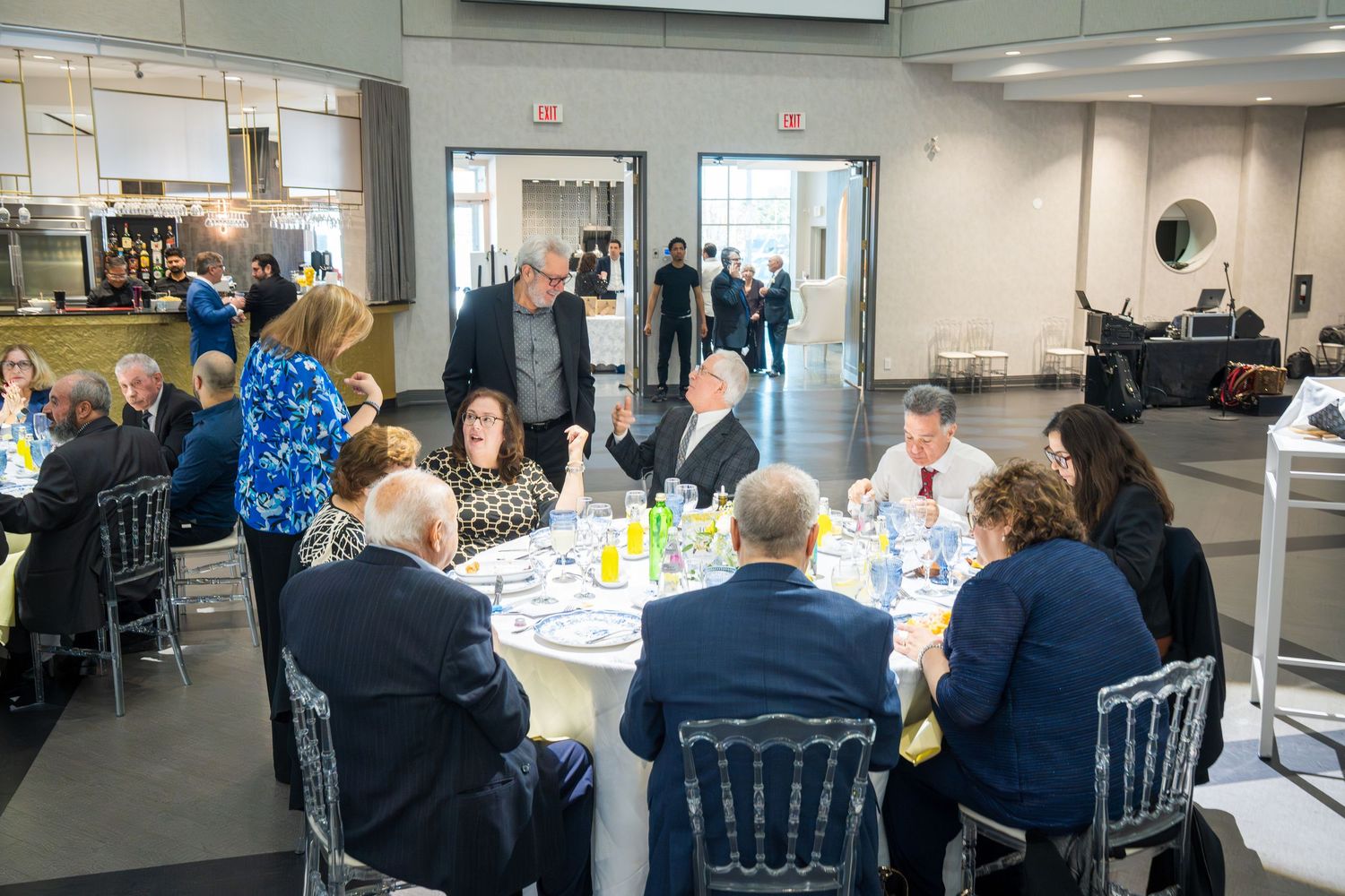 Guests seated at round tables during a formal anniversary celebration dinner in a modern event venue.