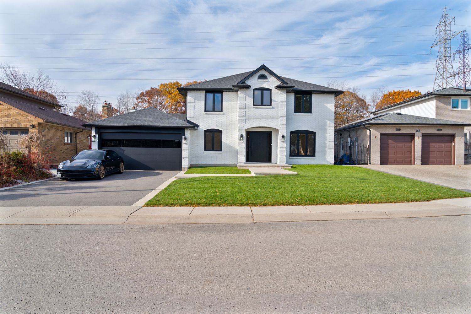 A panoramic view of a residential neighborhood with white houses and garages against a blue sky with wispy clouds.