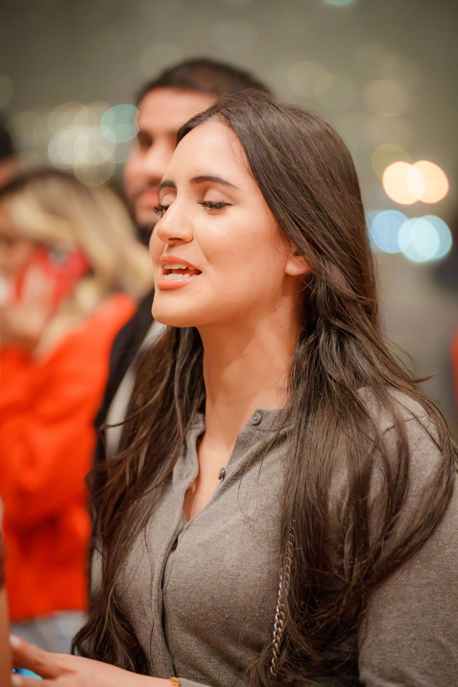 Person in a grey jacket enjoying a moment with closed eyes and flowing dark hair.