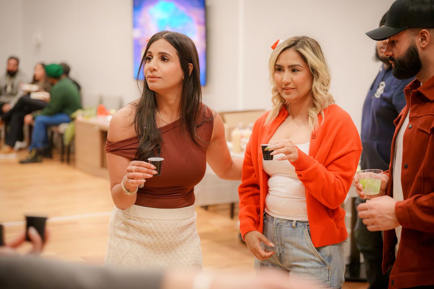 People socializing at a casual indoor party with colorful lighting.