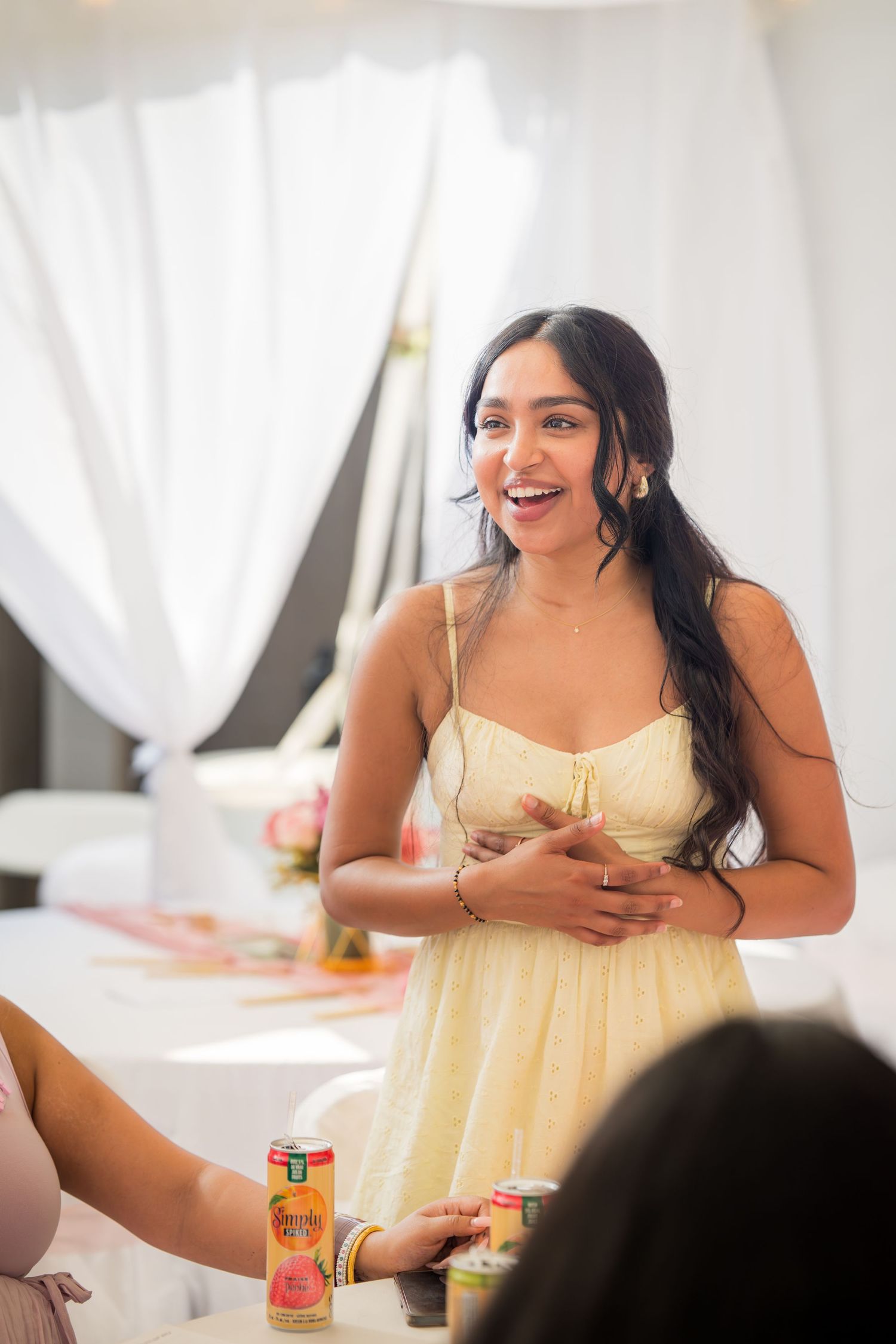 A guest in a yellow dress smiles during a baby shower celebration.