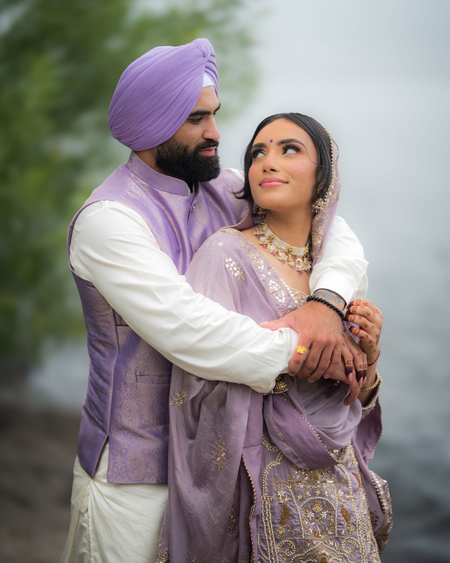 Couple in matching purple traditional outfits share intimate moment outdoors.