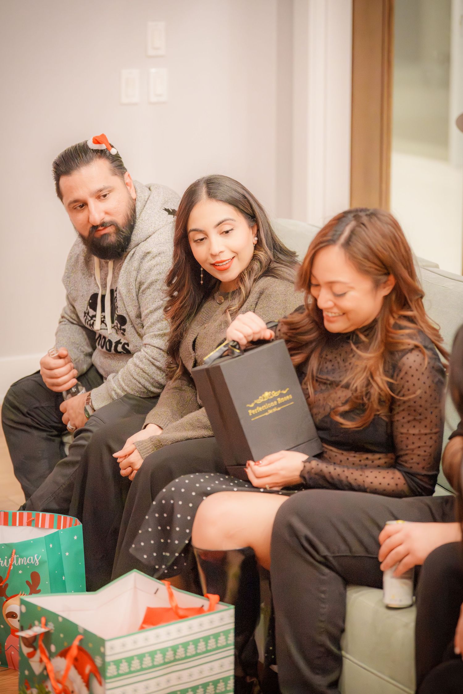 Group sitting together on a couch opening gifts and sharing holiday cheer.