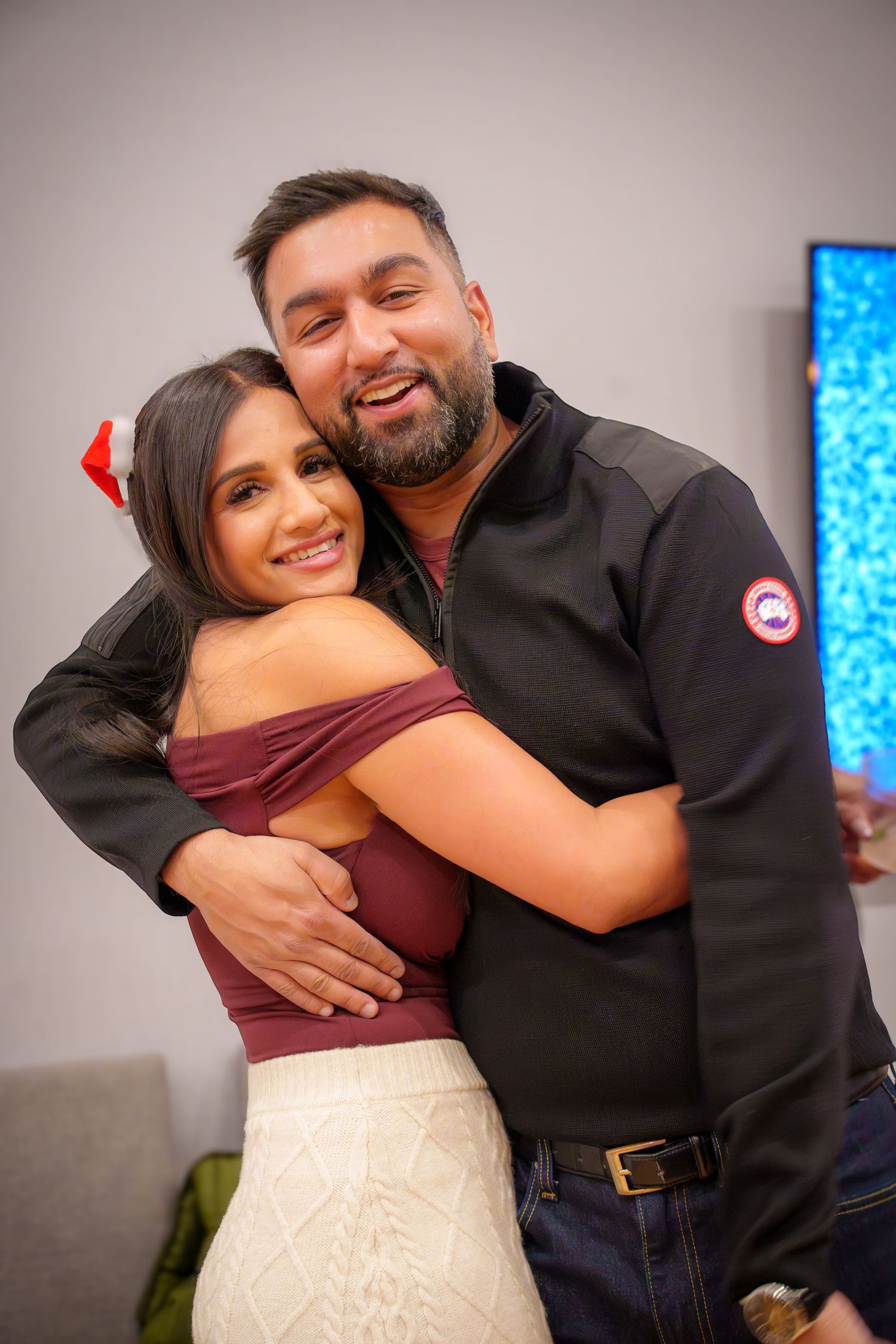 Two people share a warm embrace while celebrating at an indoor event.