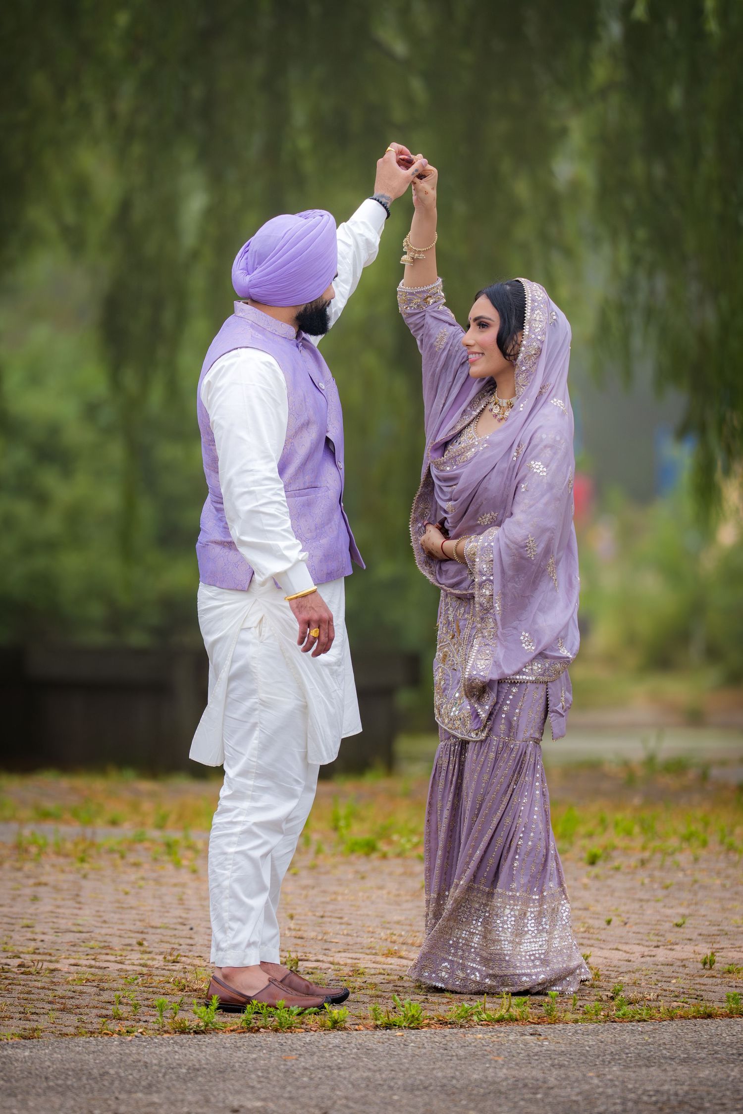 Couple in traditional Punjabi attire shares a playful moment during their outdoor photoshoot.