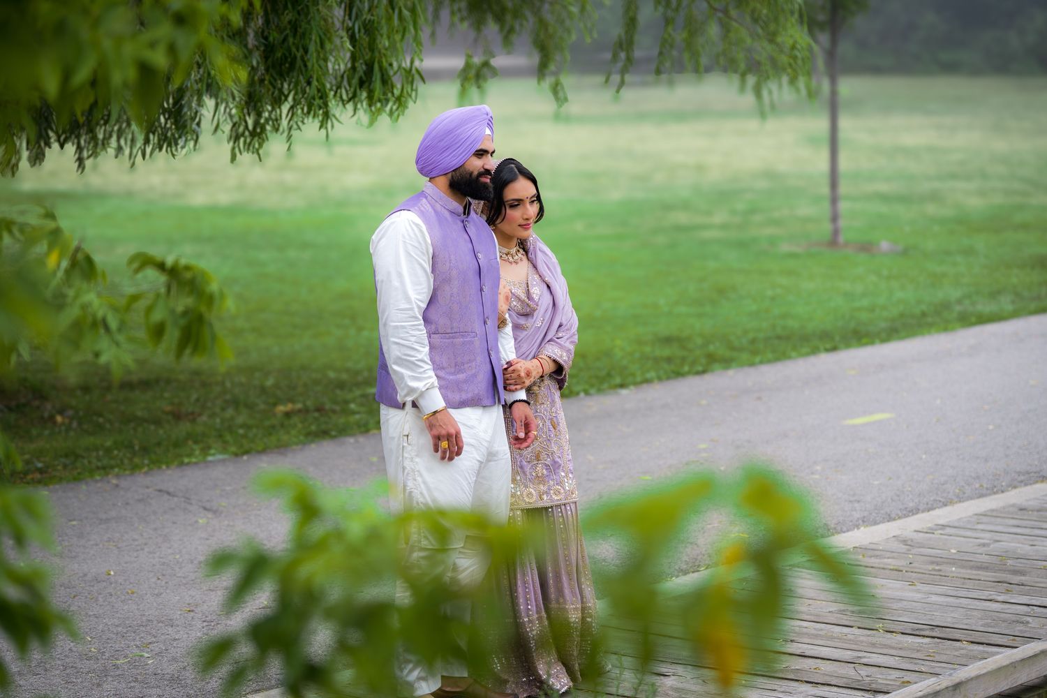 A romantic outdoor photoshoot in traditional Punjabi outfits with lavender and white color coordination.