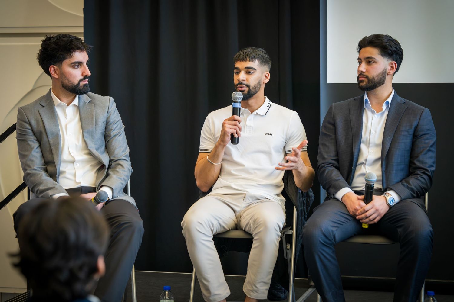 Business professionals engaged in conversation while seated on stage during panel event.
