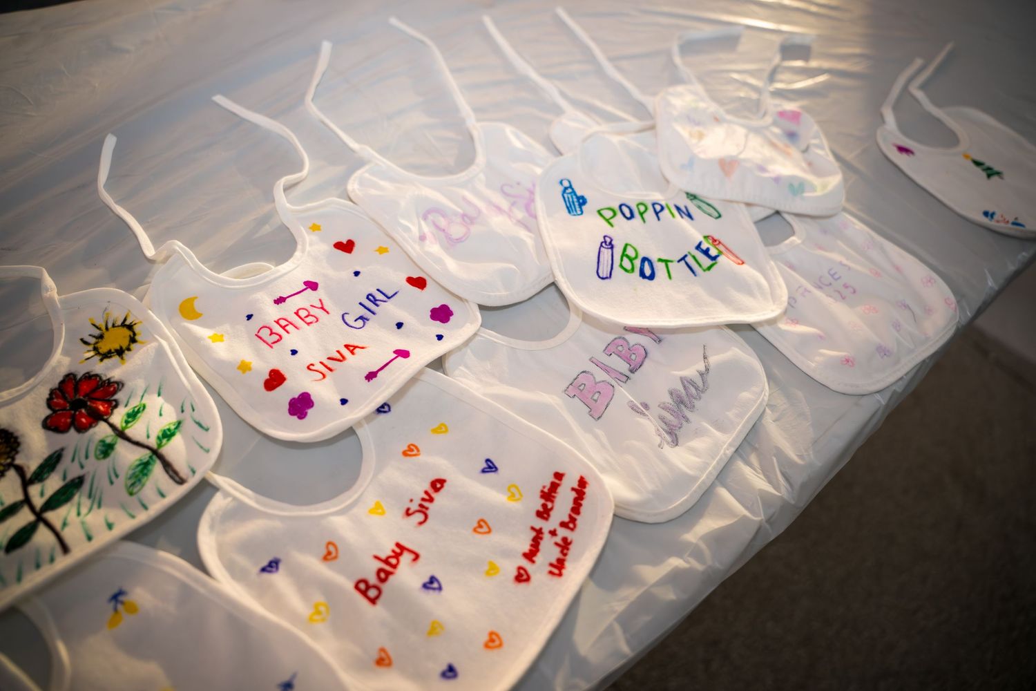 Row of decorated white baby bibs laid out on display with colorful embellishments.