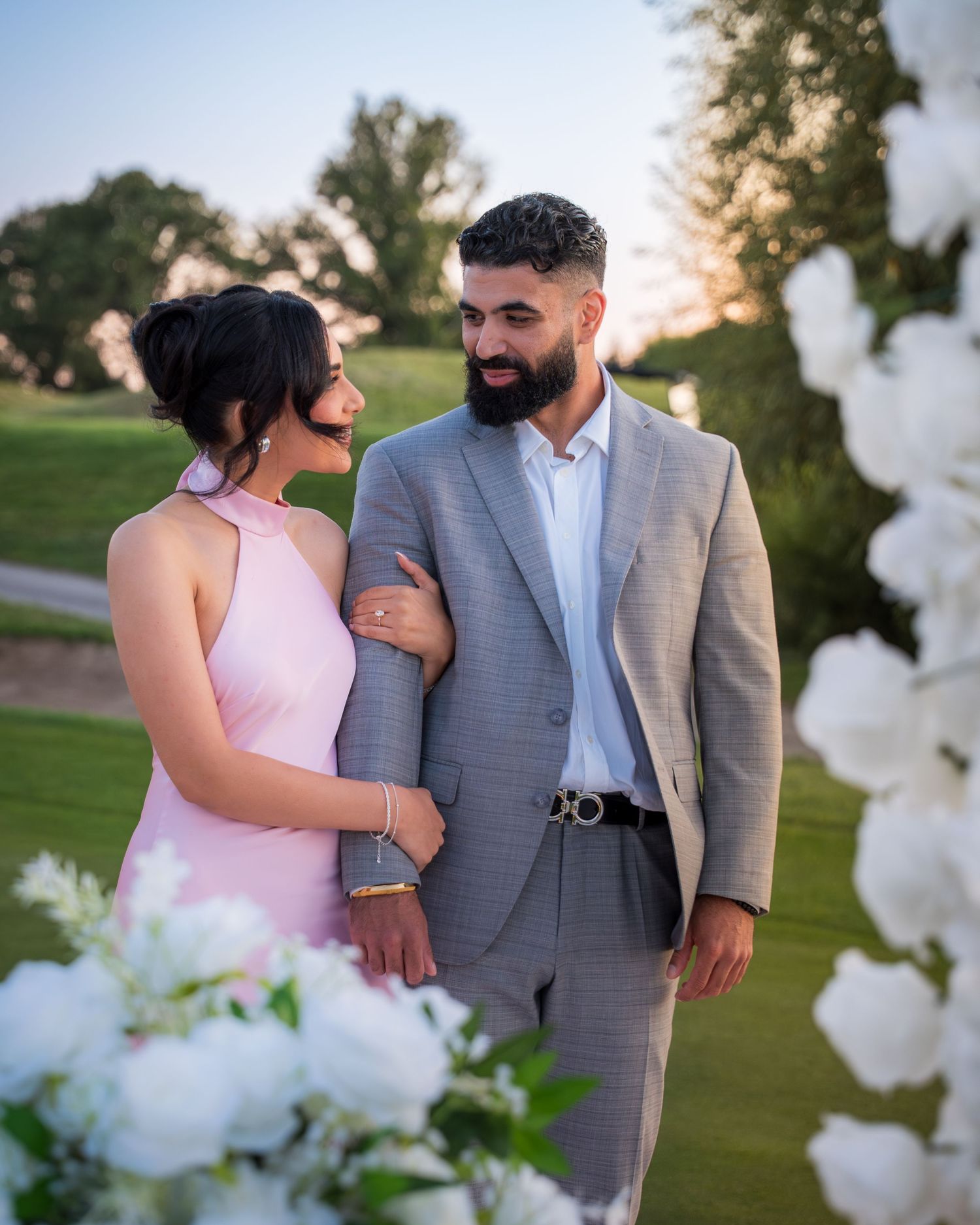 Romantic couple embraces during golden hour photoshoot with floral decorations.