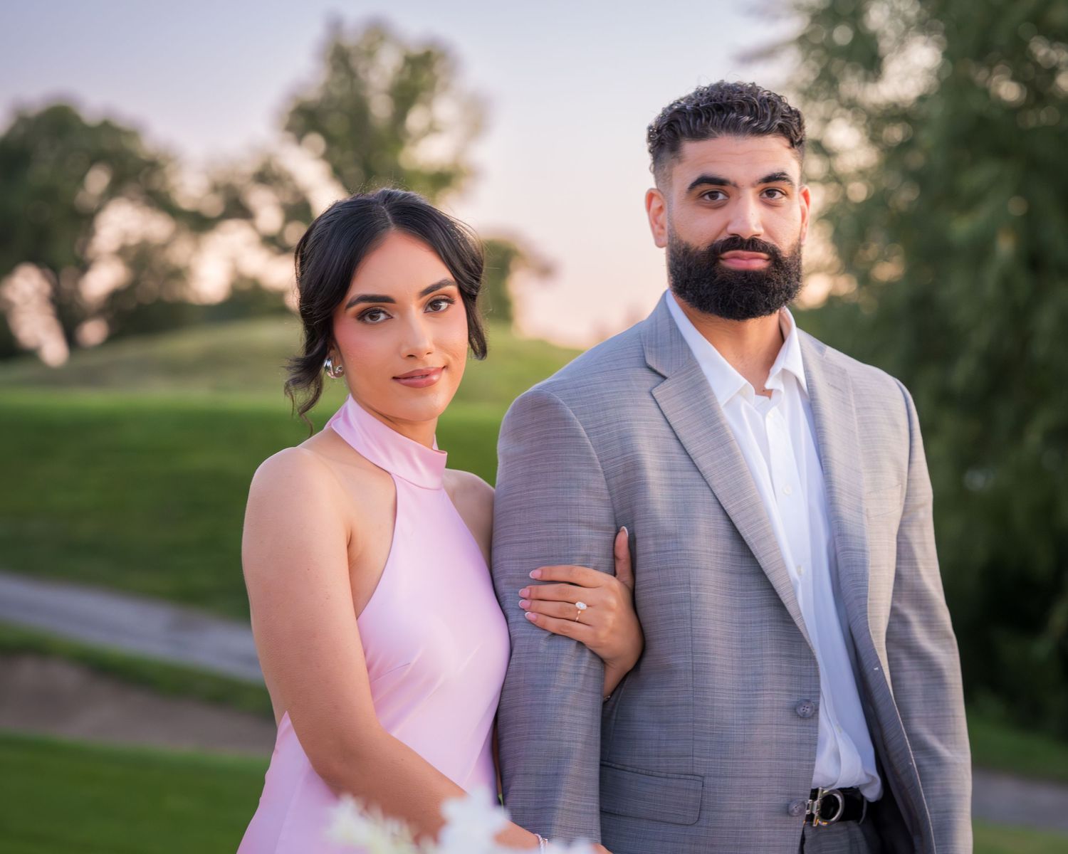 Romantic sunset photoshoot with couple in pink dress and grey suit.