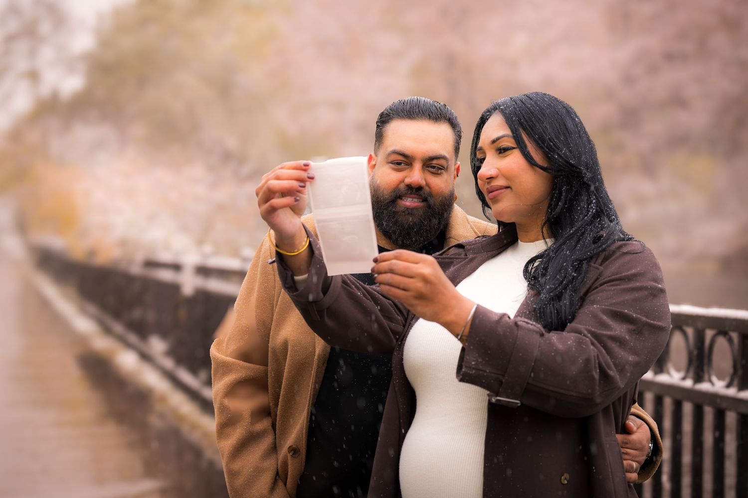 Couple embracing while looking at photographs together on a rustic bridge.
