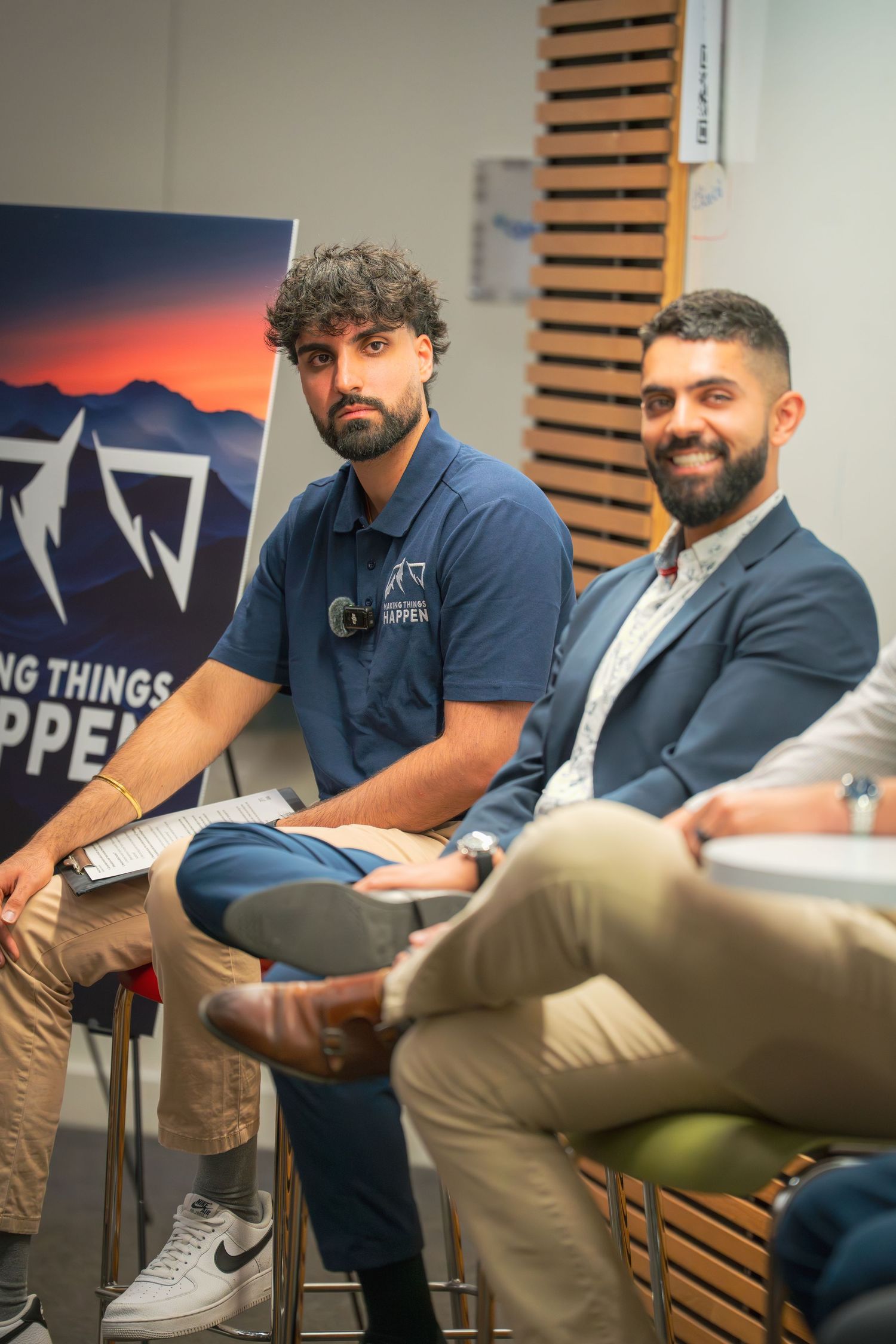 Group of professionals seated in a row during a business meeting with decorative wall panels.